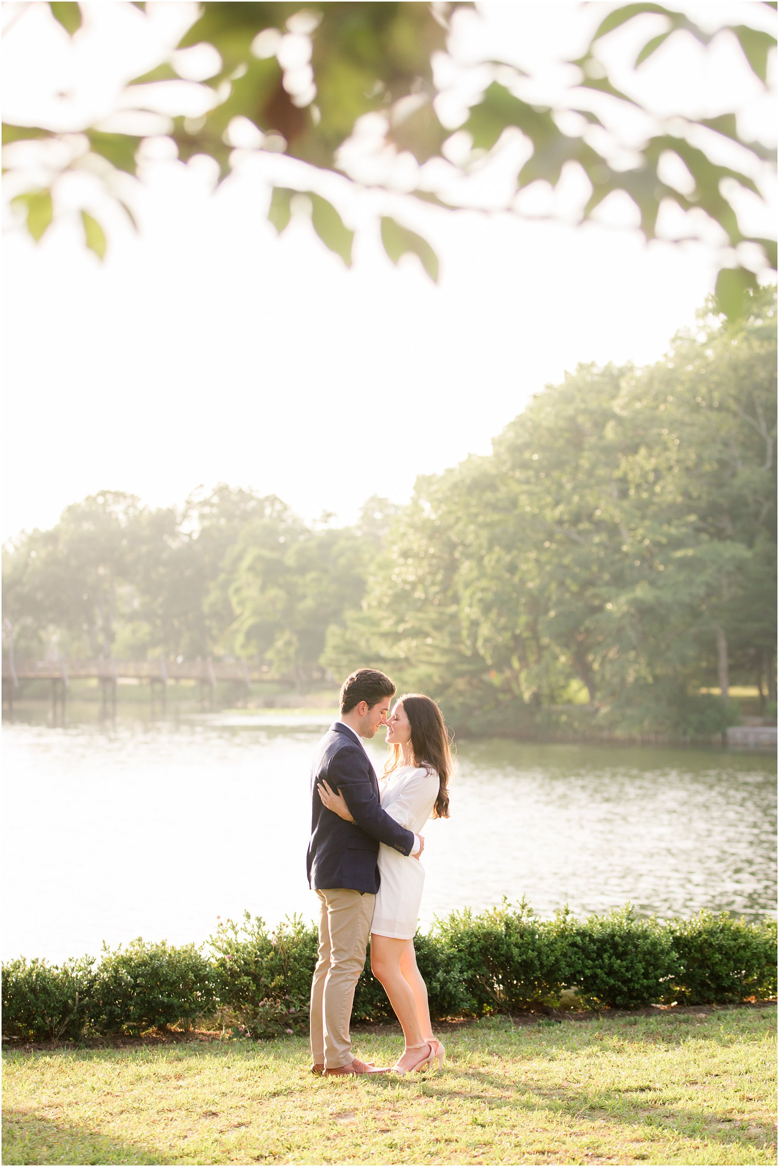 bride and groom stand nose to nose by lake in New Jersey