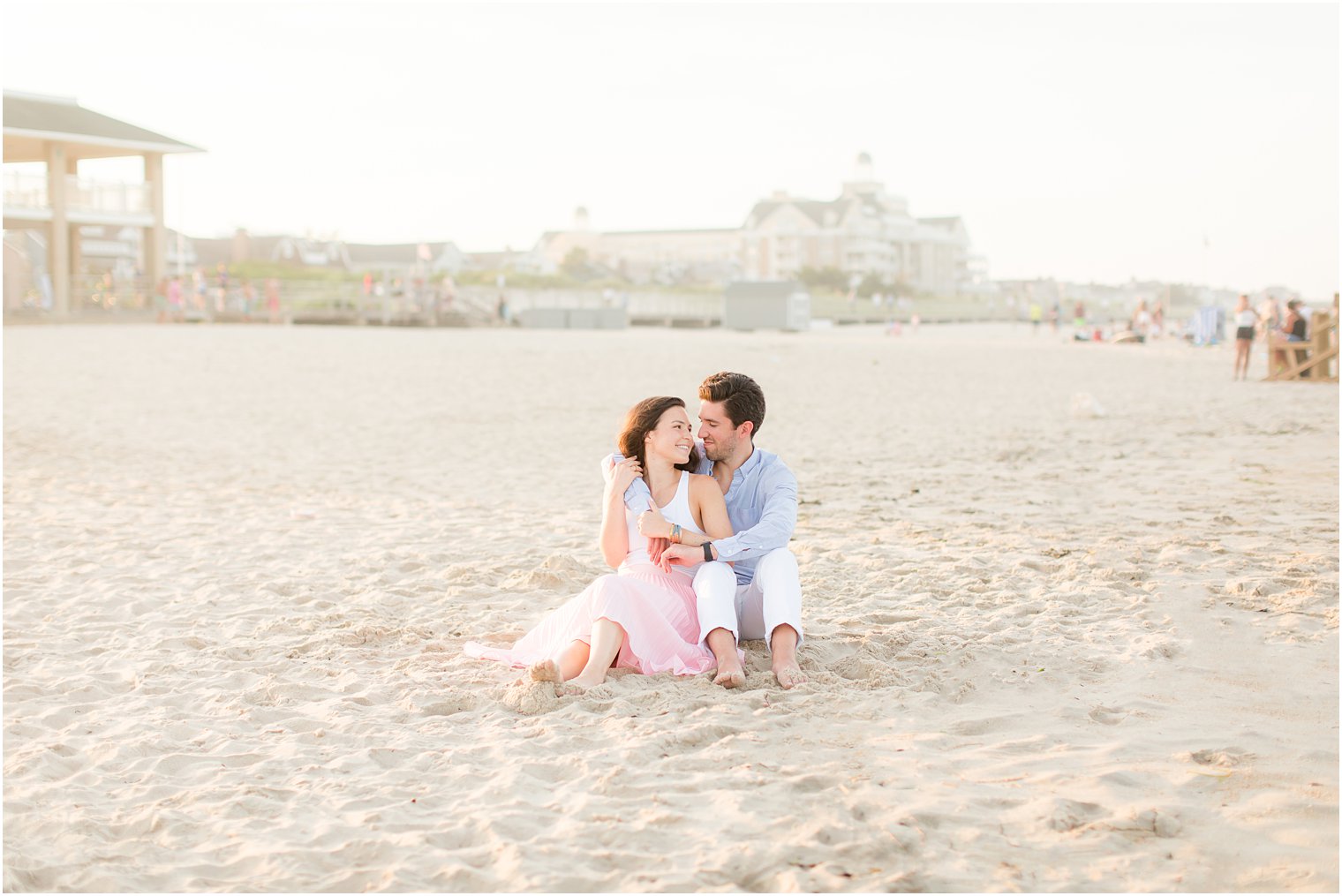 engaged couple sits on beach in New Jersey