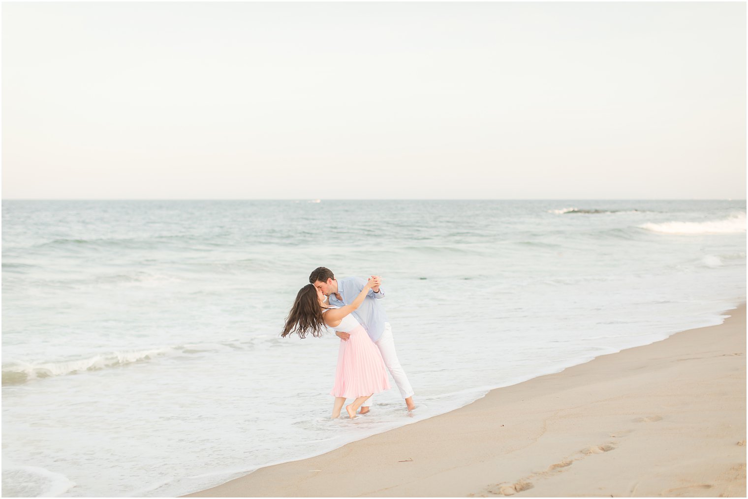 groom kisses fiancee in the water and dips her