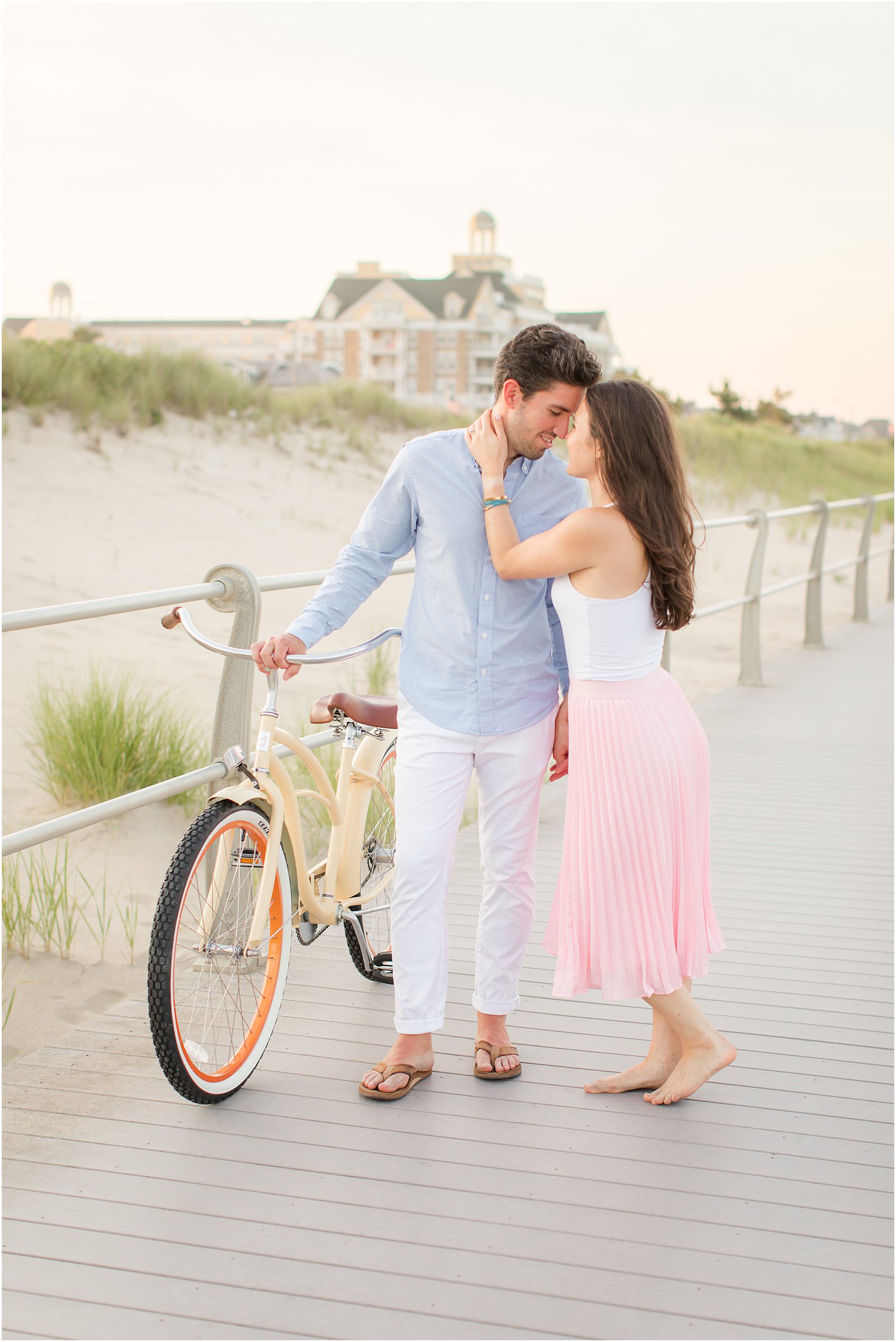 engaged couple stands nose to nose during boardwalk engagement session in New Jersey