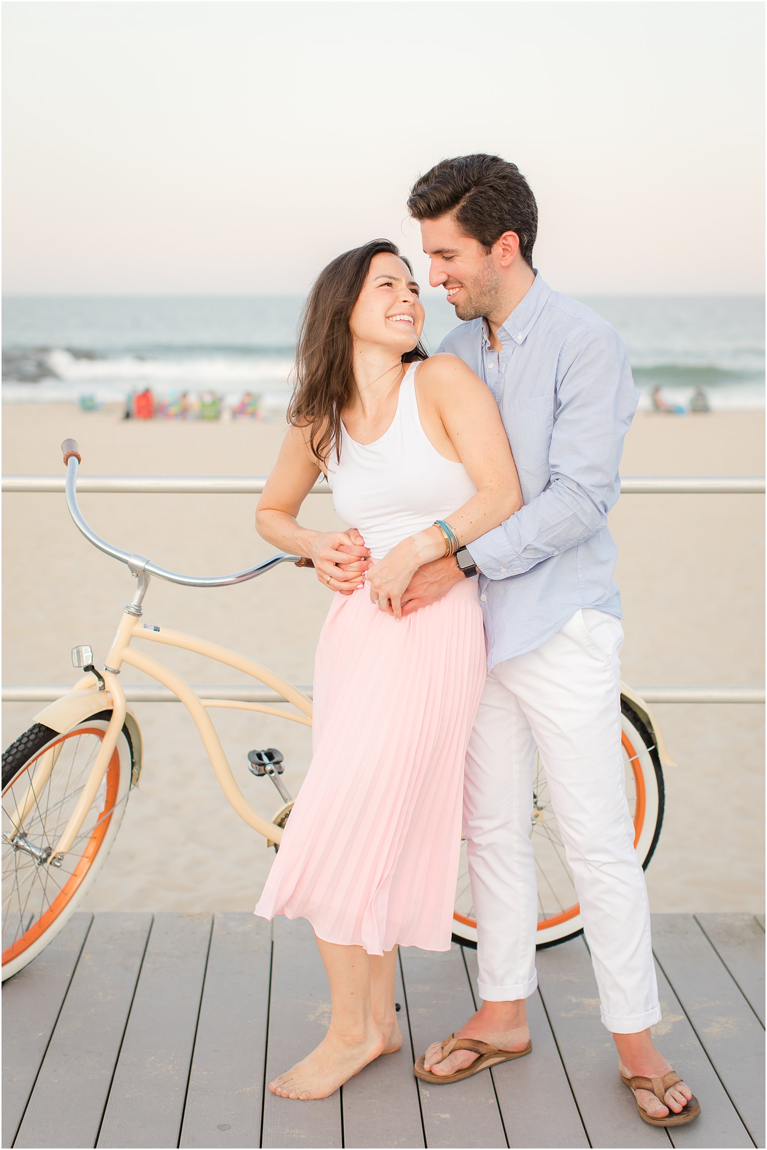 bride and groom stand by bike on New Jersey boardwalk in the summer