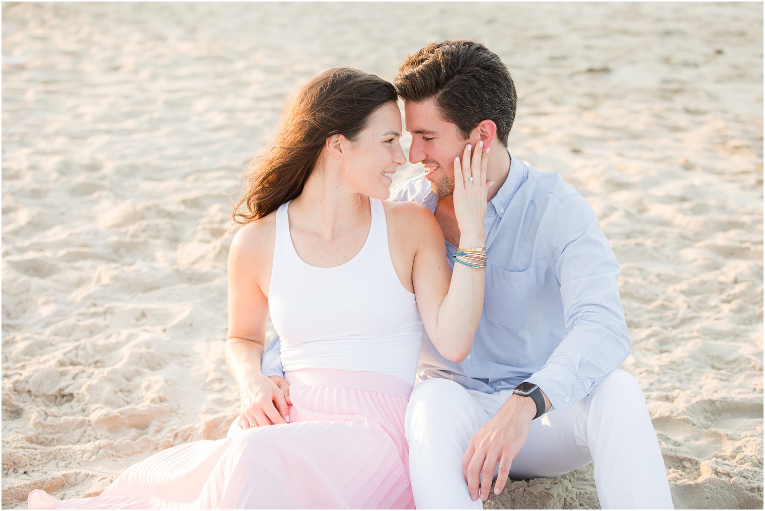 engaged couple sits in sand during Spring Lake NJ Engagement Session