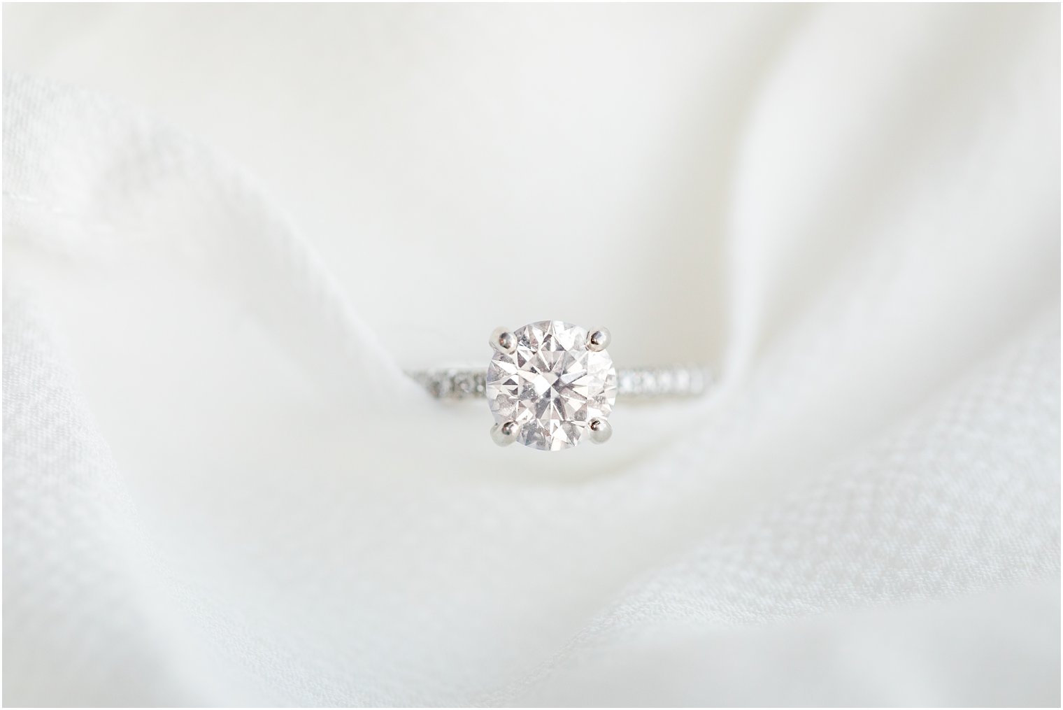 elegant and simple engagement ring photographed on white fabric