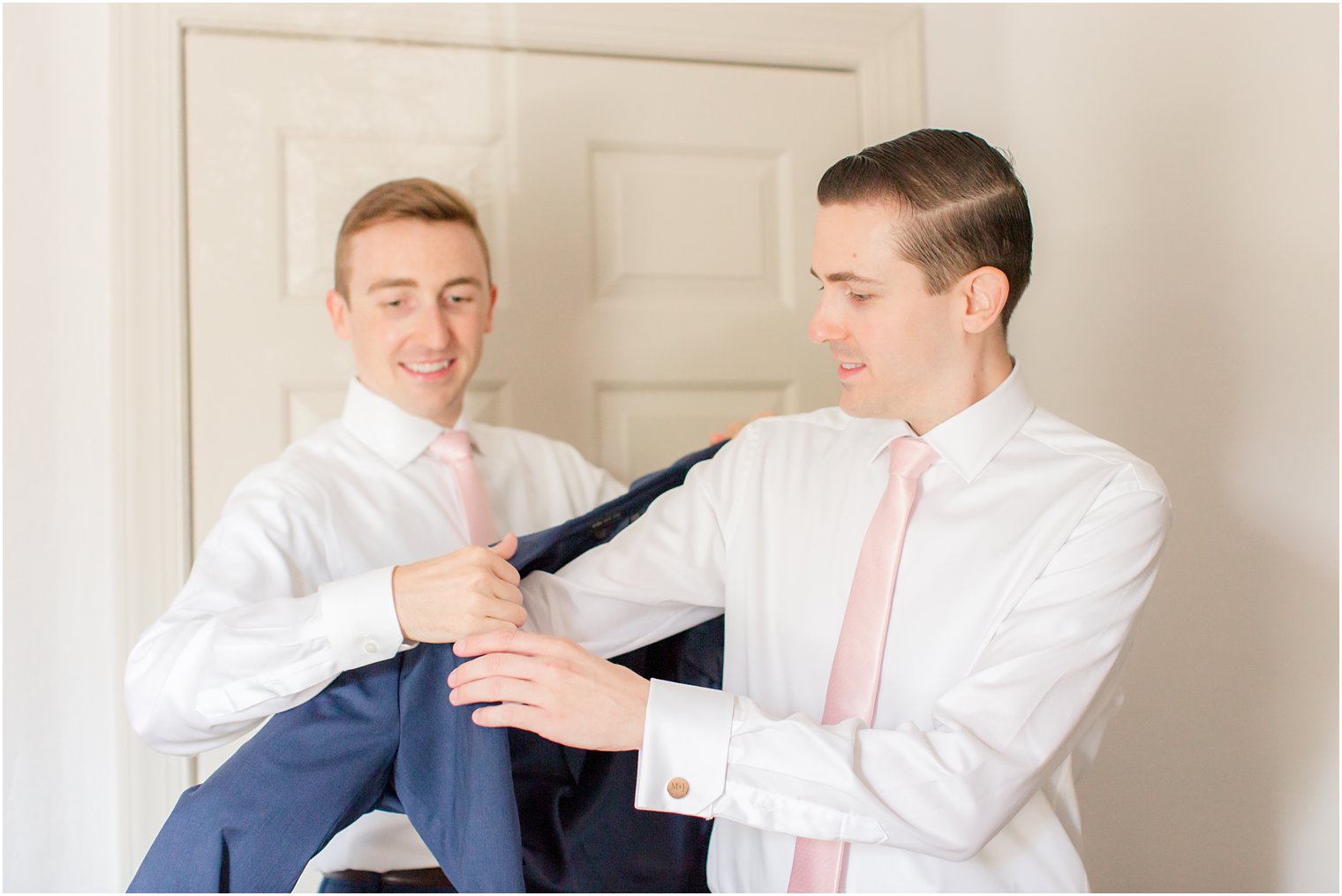 Best man helping groom get dressed 