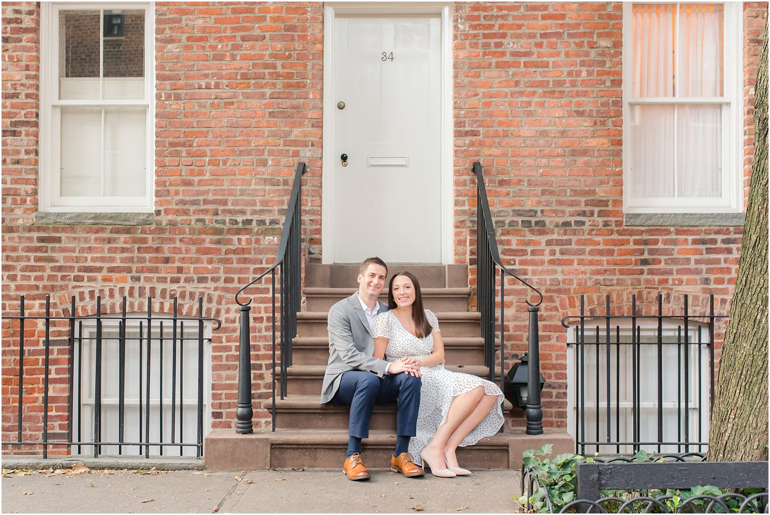 couple poses outside West Village home during engagement photos
