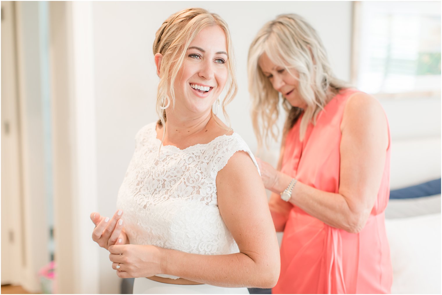 bride's mother adjusts back of wedding dress for the bride