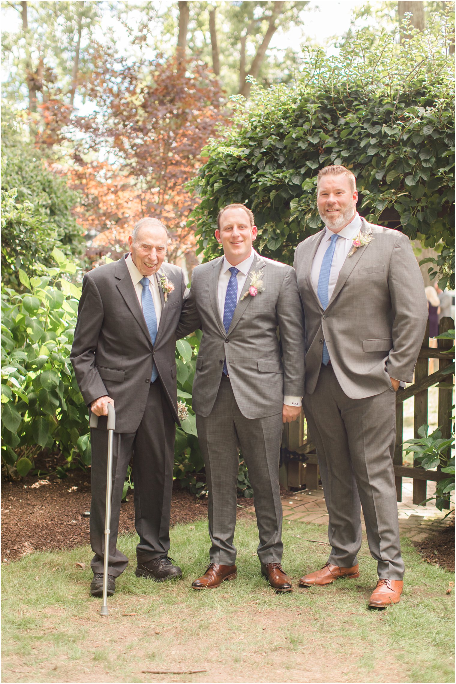 groom poses with family before Westfield NJ backyard wedding