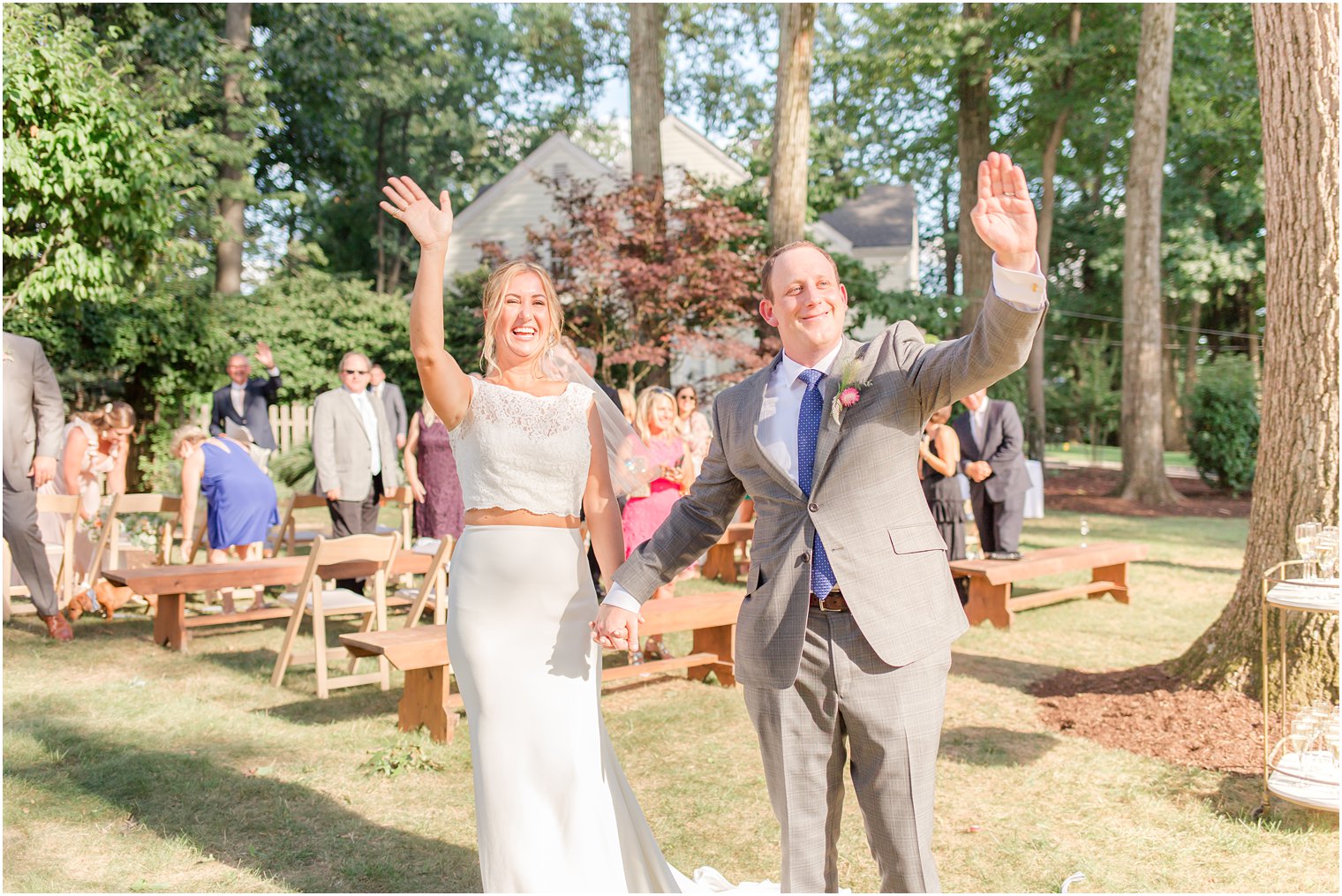 newlyweds wave after wedding ceremony in backyard