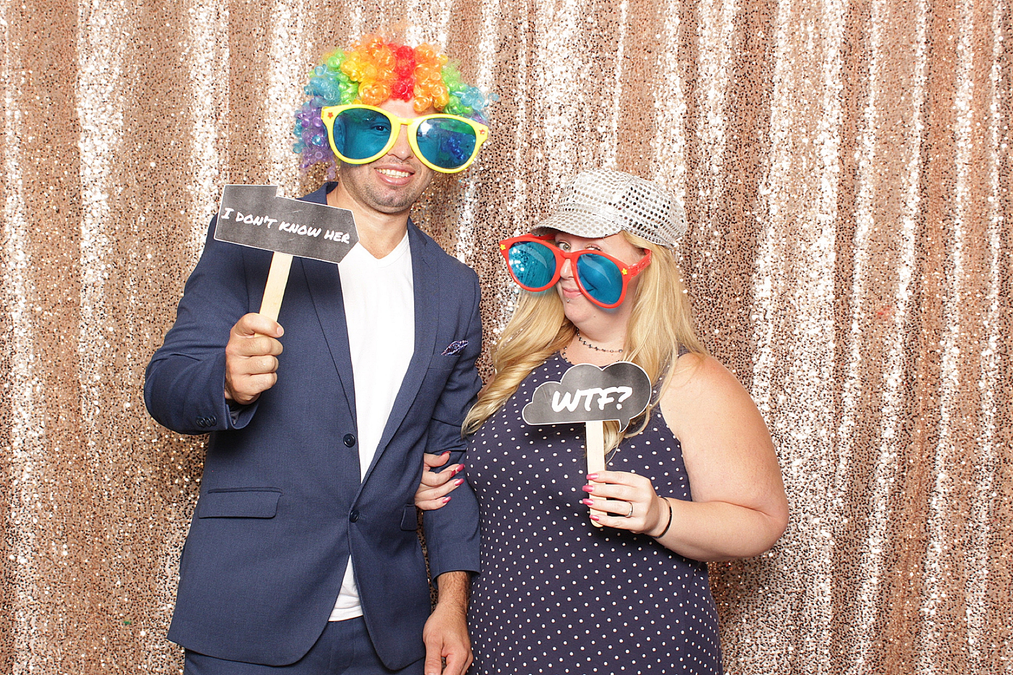 guests hold signs and wear wigs during Clarks Landing Yacht Club wedding photo booth by Idalia Photography