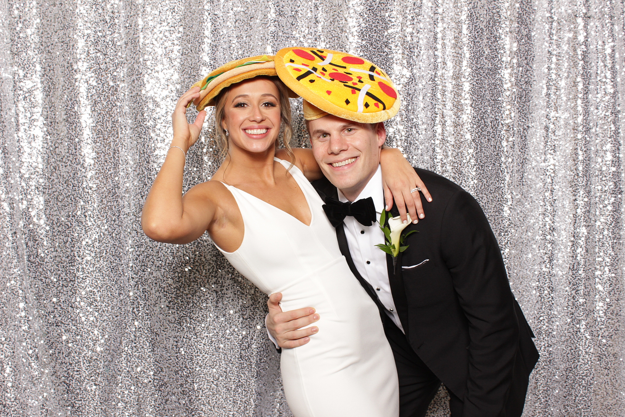 newlyweds in pizza hats laugh in photo booth