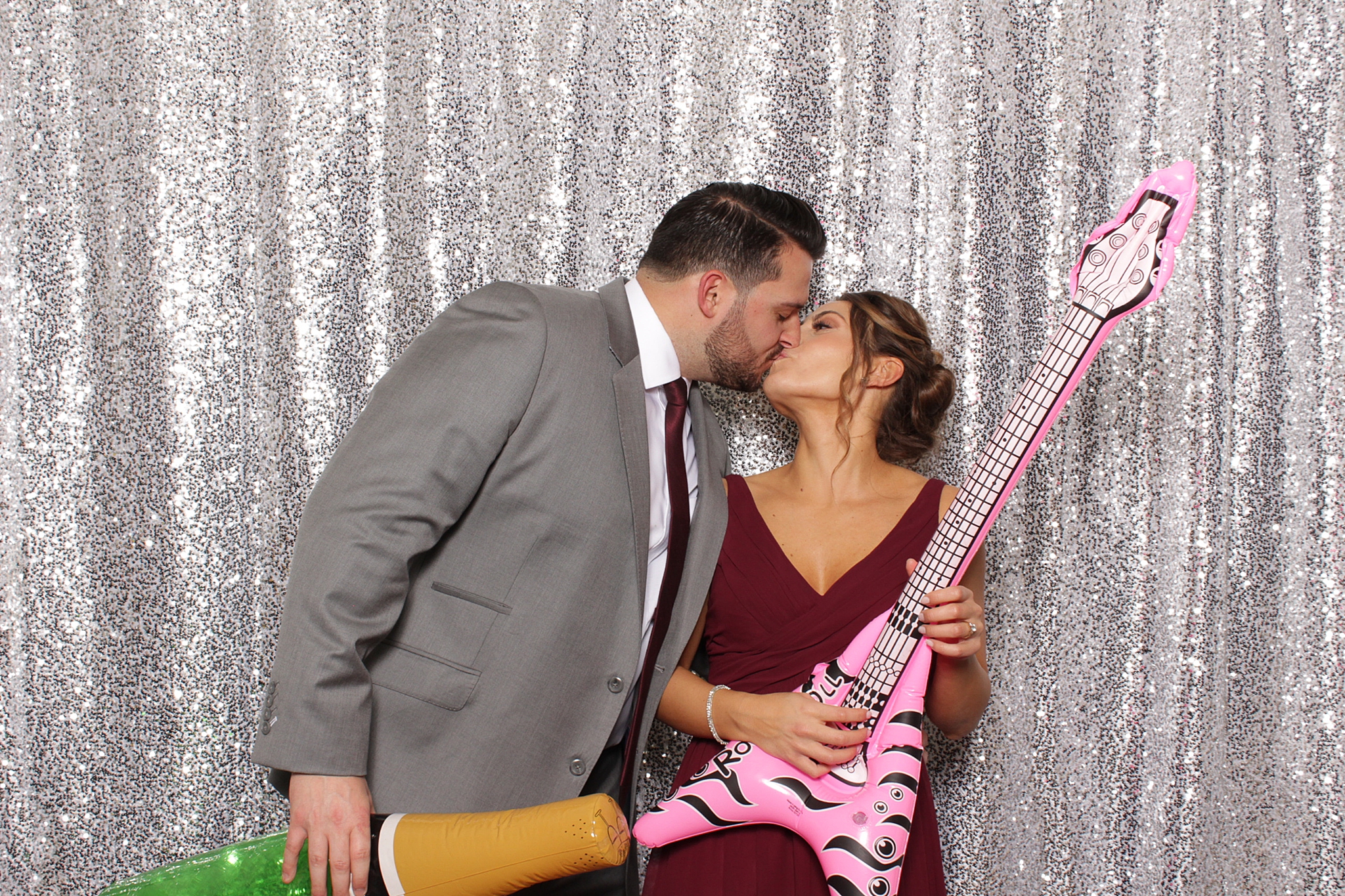 wedding guests kiss in photo booth with inflatable guitar