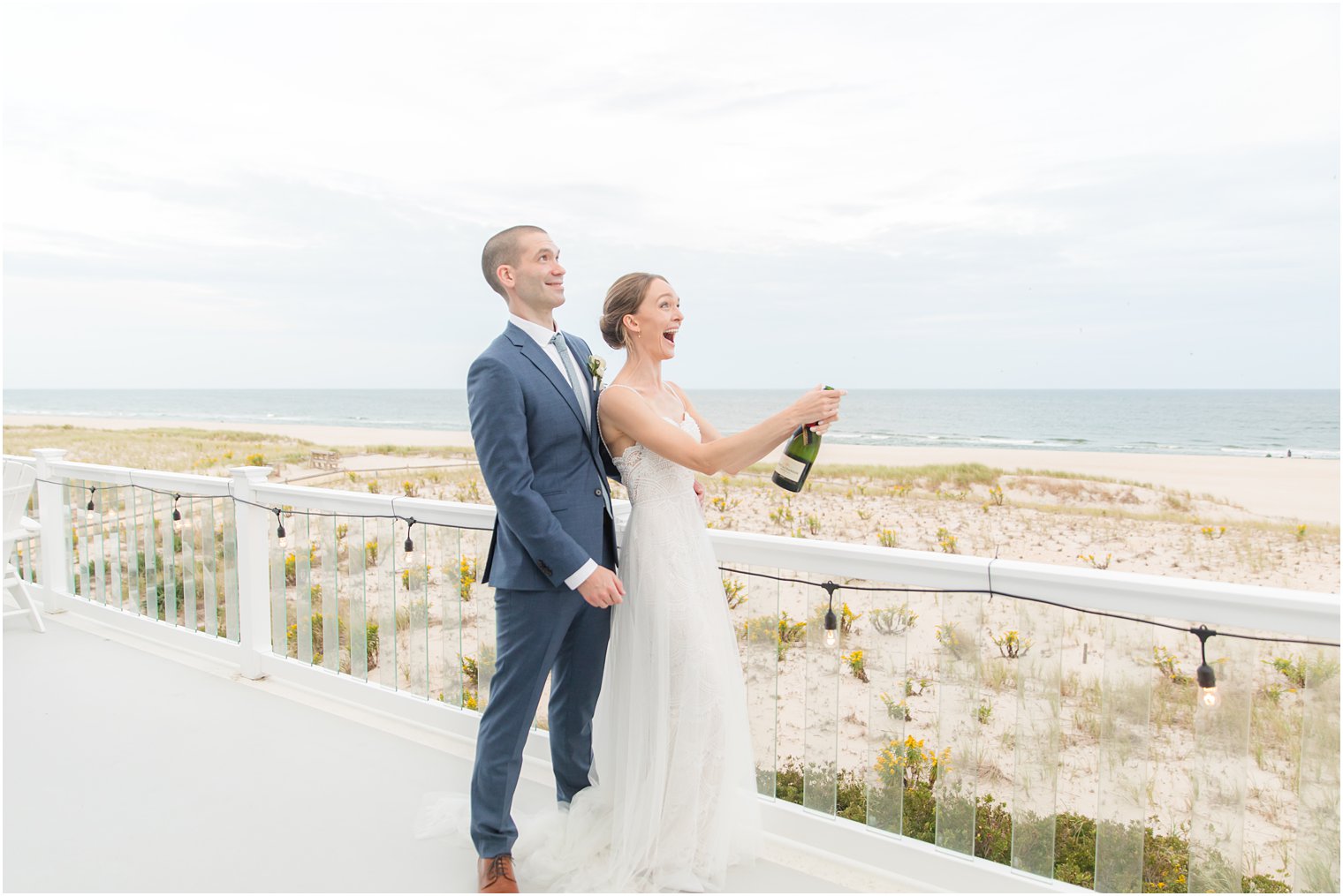 newlyweds pop champagne overlooking beach