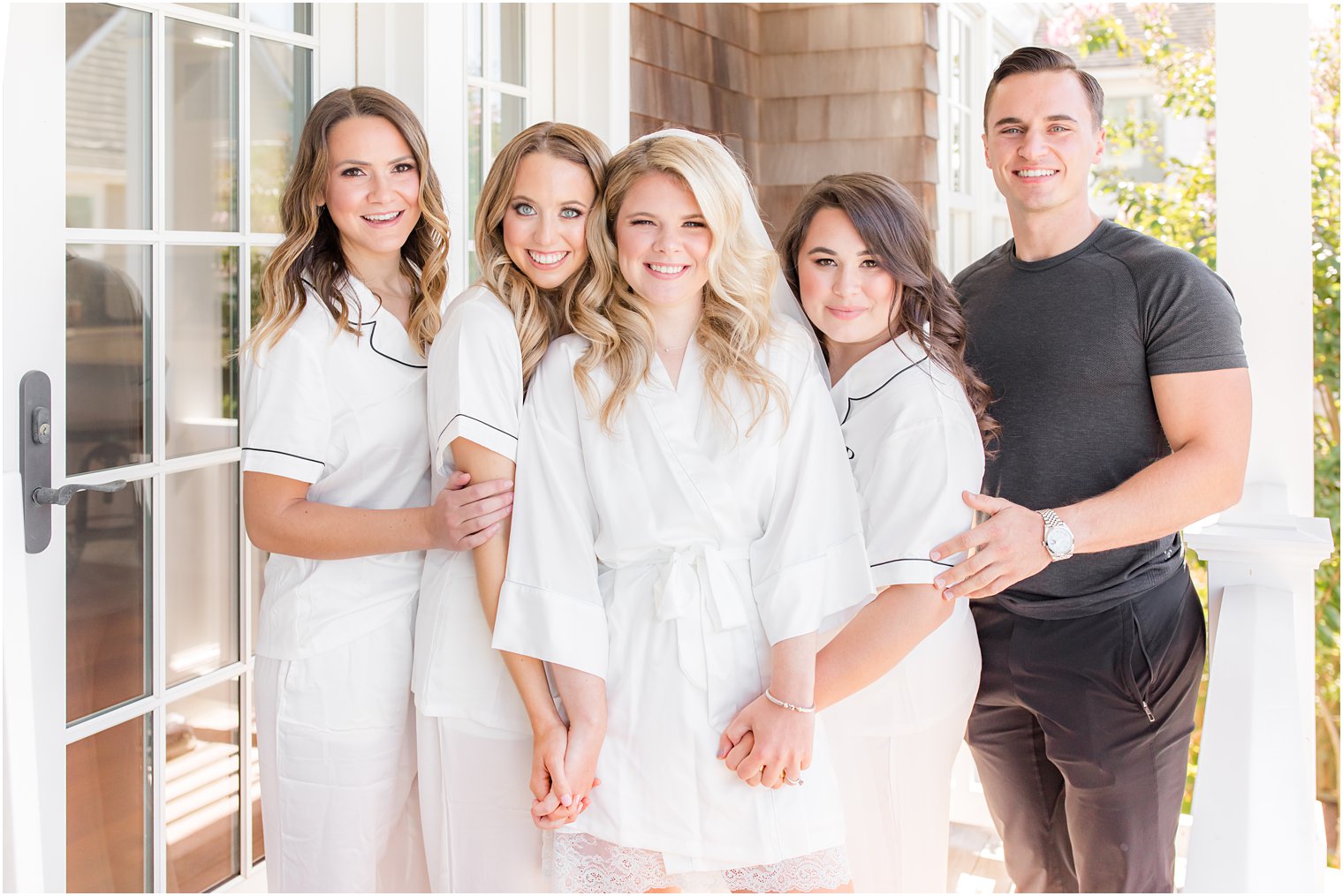 bride poses with bridesmaids and man of honor