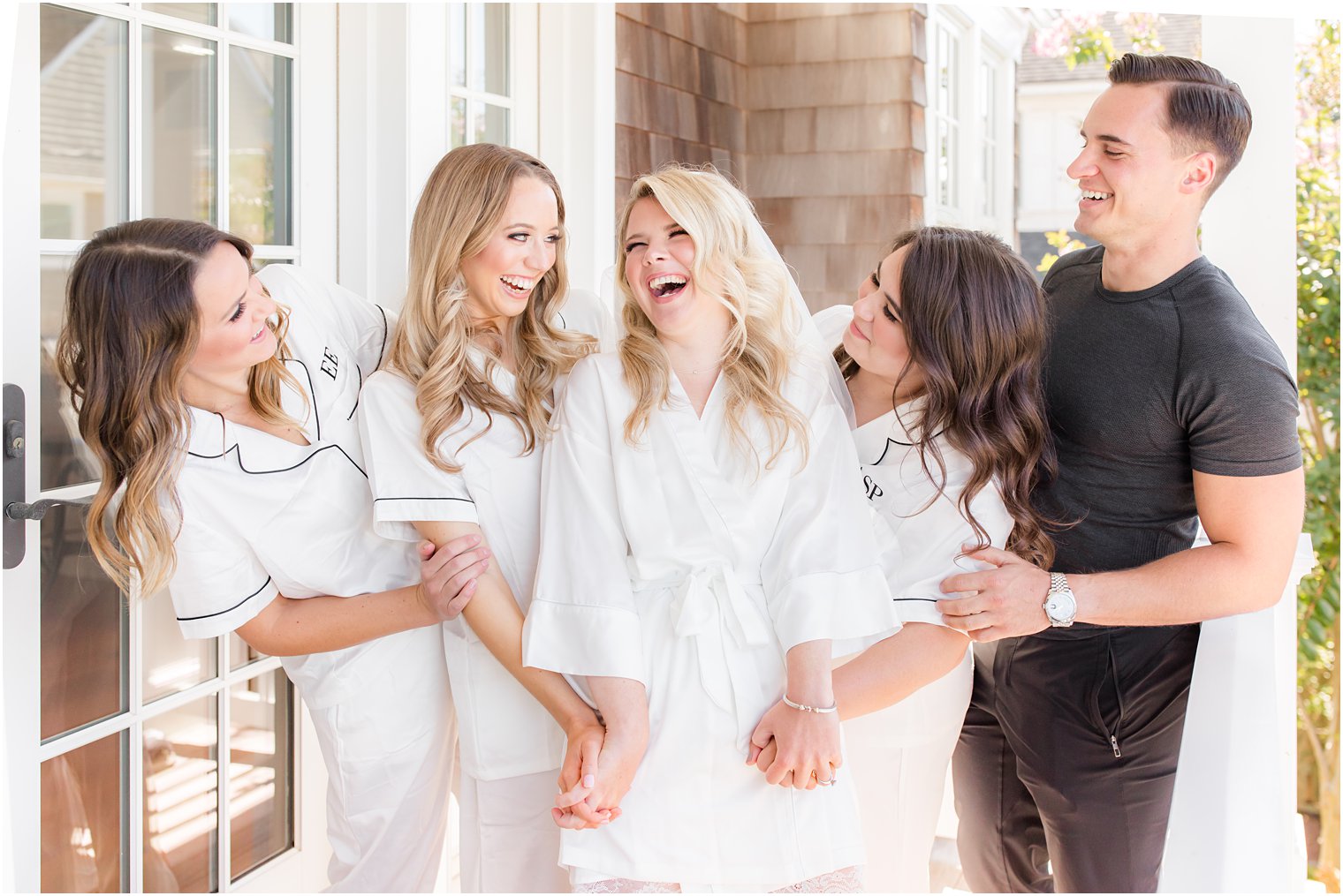 bride laughs with bridal party while preparing for wedding