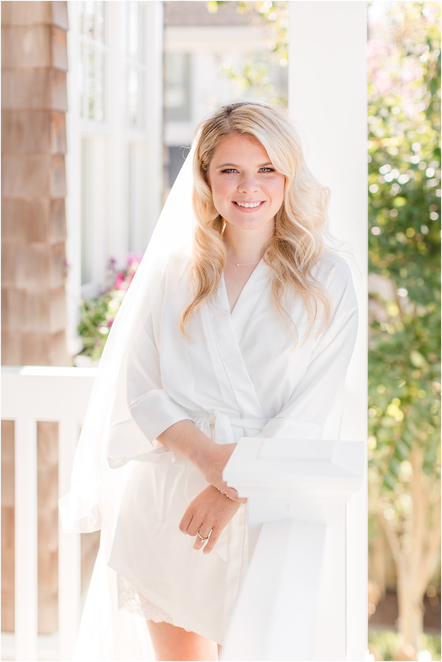 bride poses in robe and veil before Mantoloking Yacht Club wedding