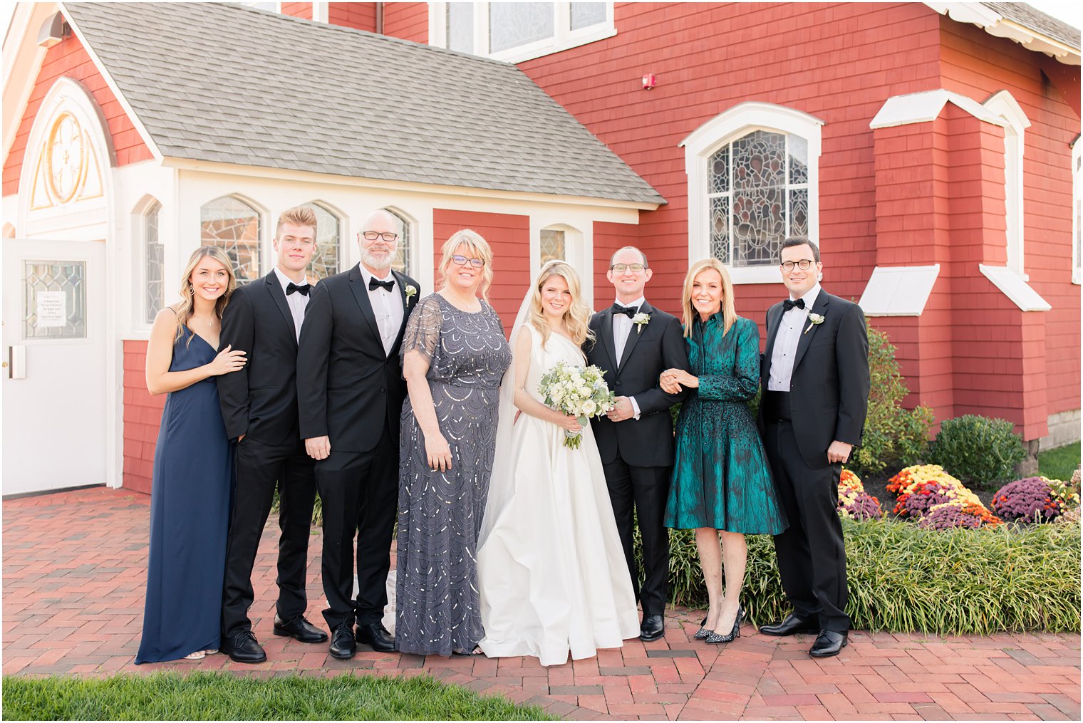 family poses outside New Jersey church with bride and groom