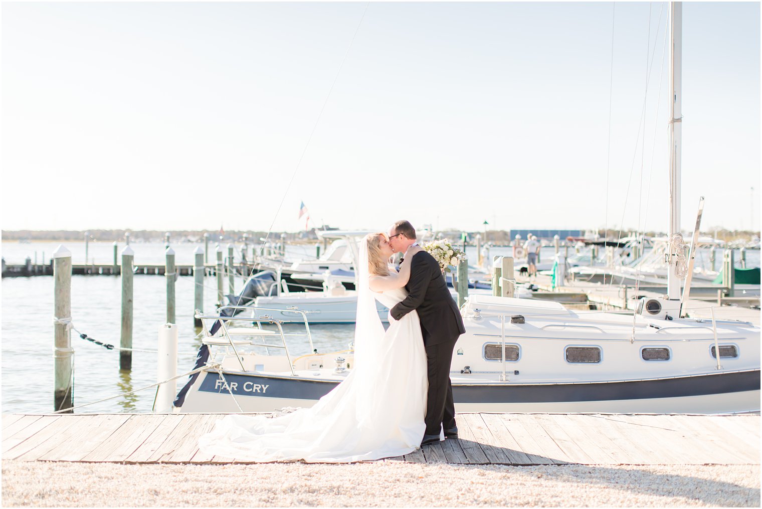 bride and groom kiss on pier at Mantoloking Yacht Club