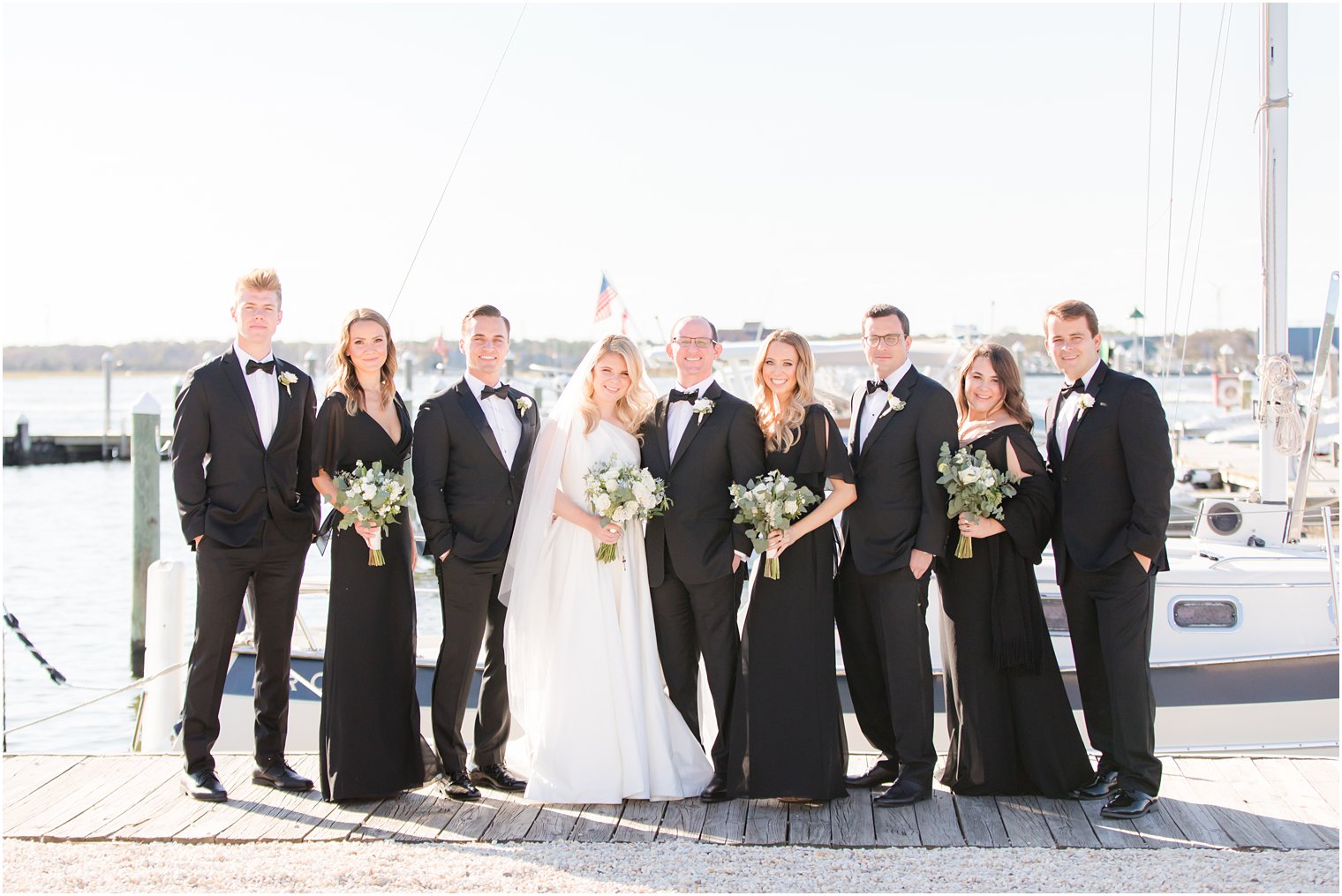 bride and groom pose with bridal party in black dresses and tuxes