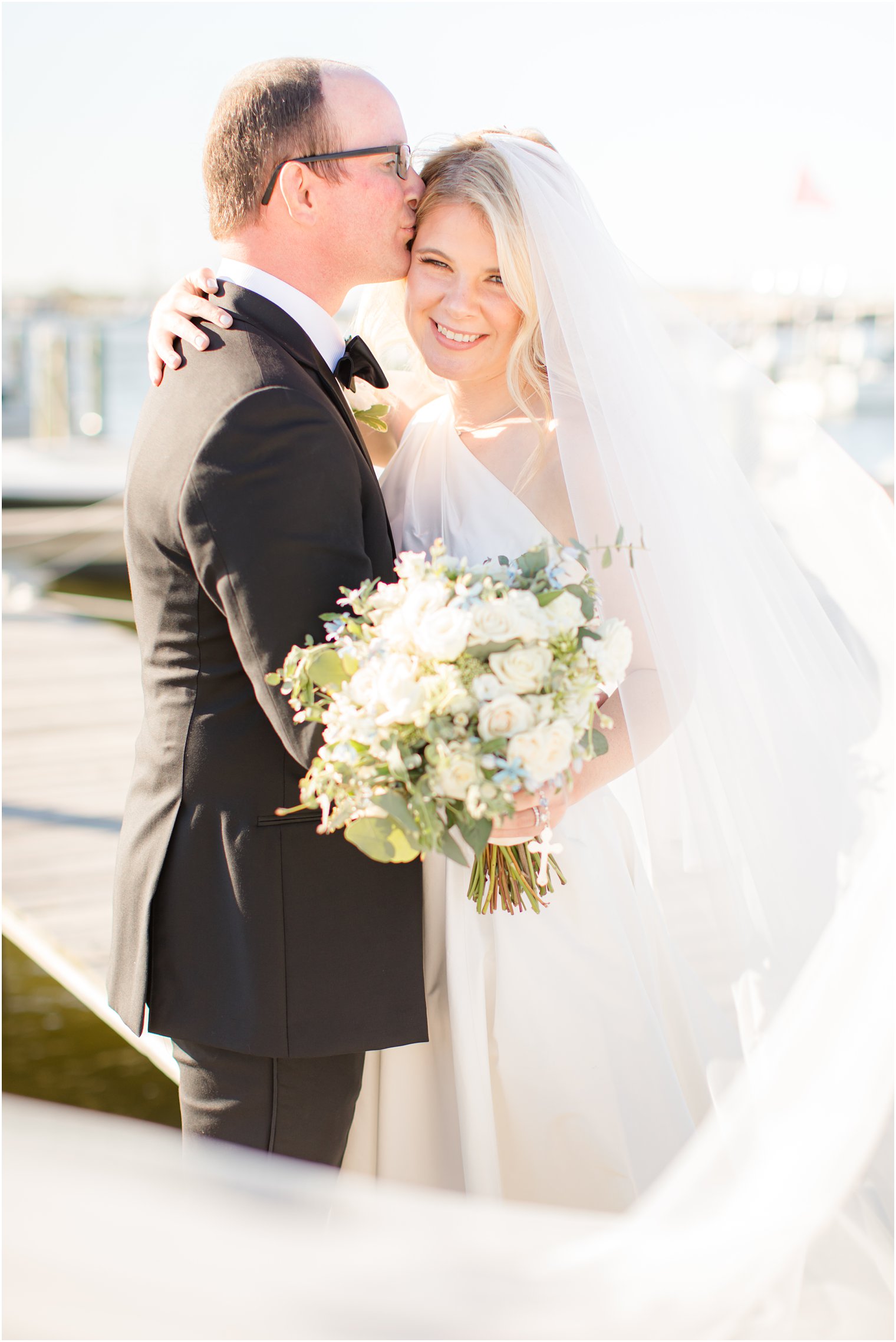 groom kisses bride on forehead during Mantoloking Yacht Club wedding photos