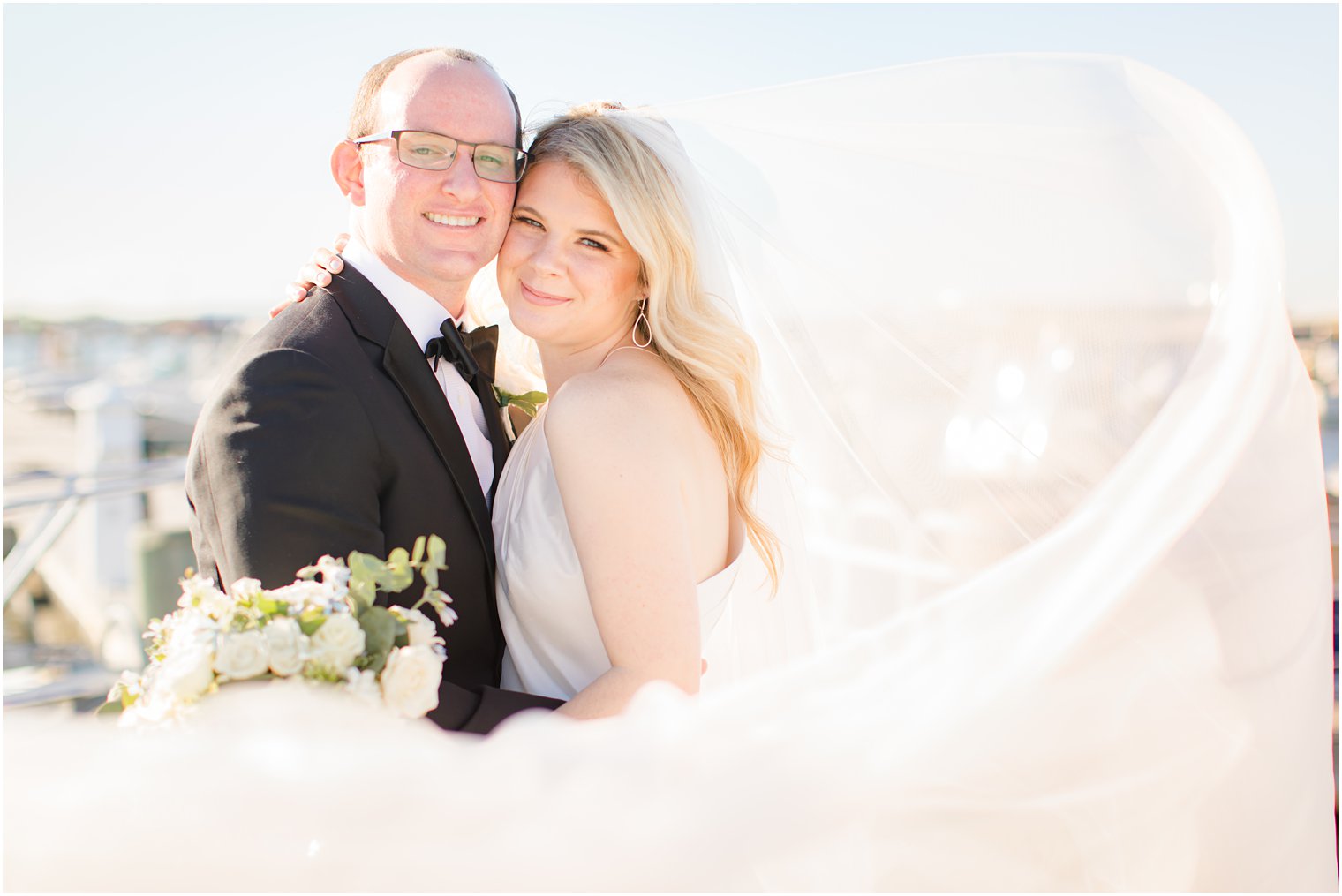 bride and groom pose with veil wrapped around them