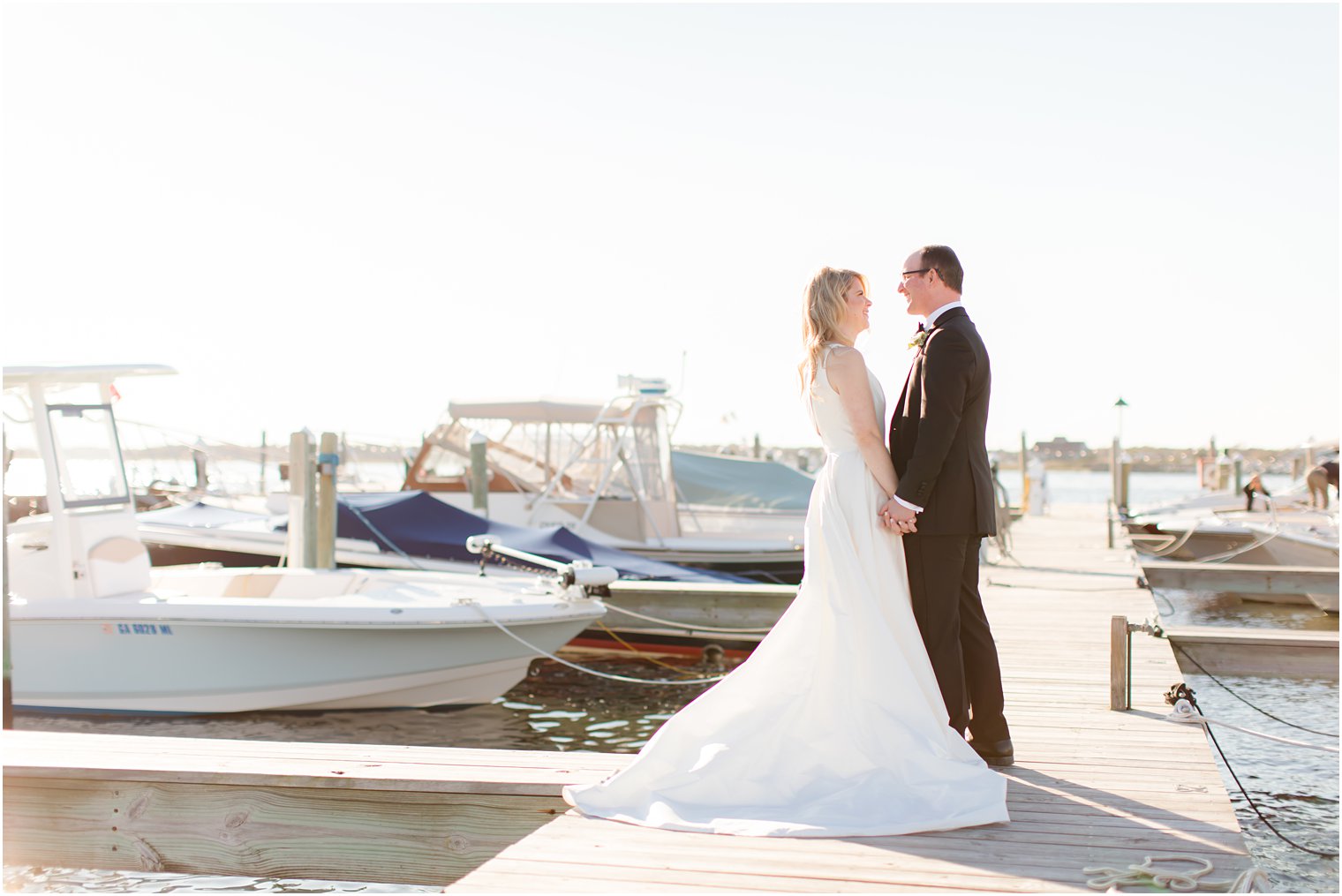 bride and groom pose on pier at Mantoloking Yacht Club