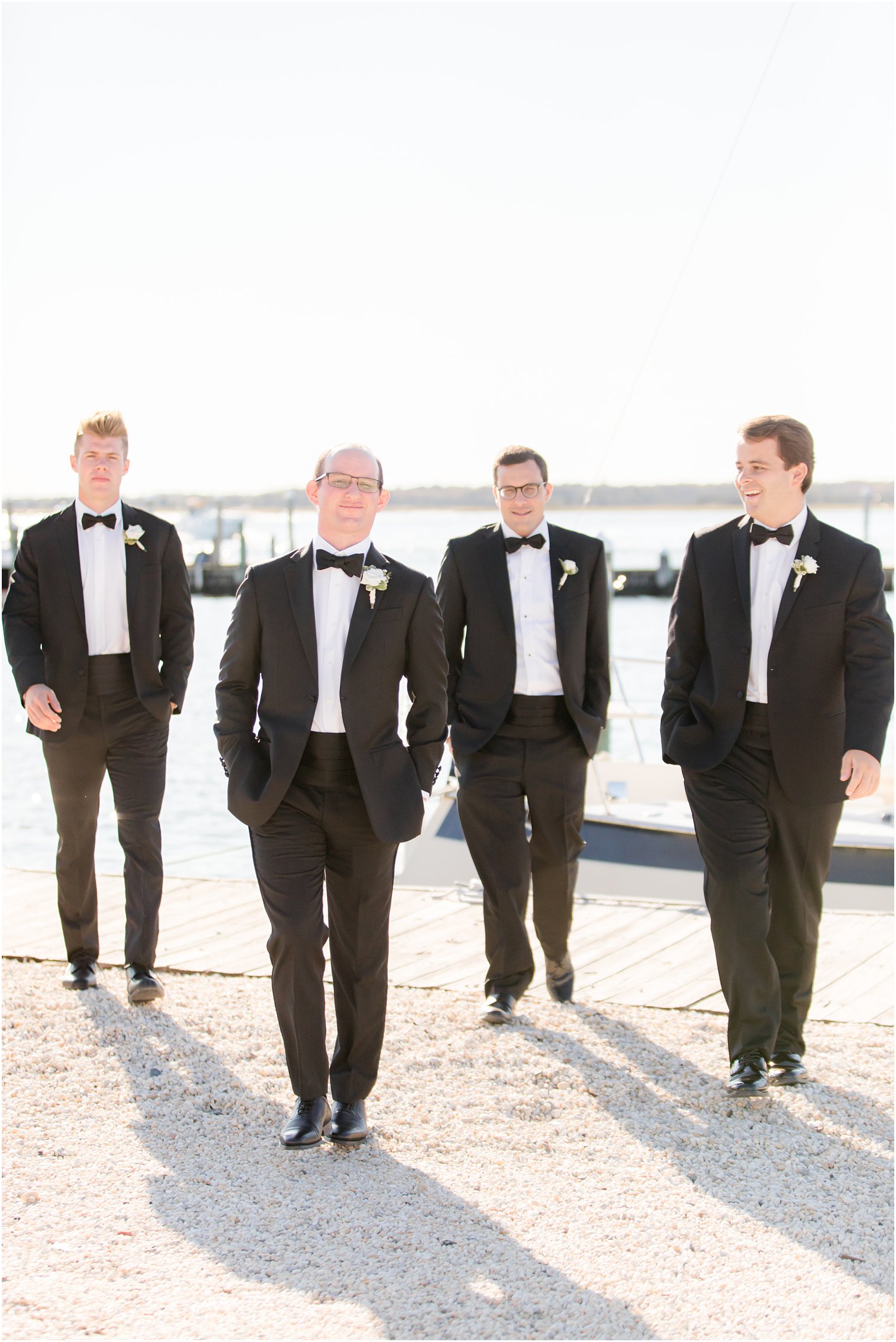 groom and groomsmen walk in black tuxes along Bay