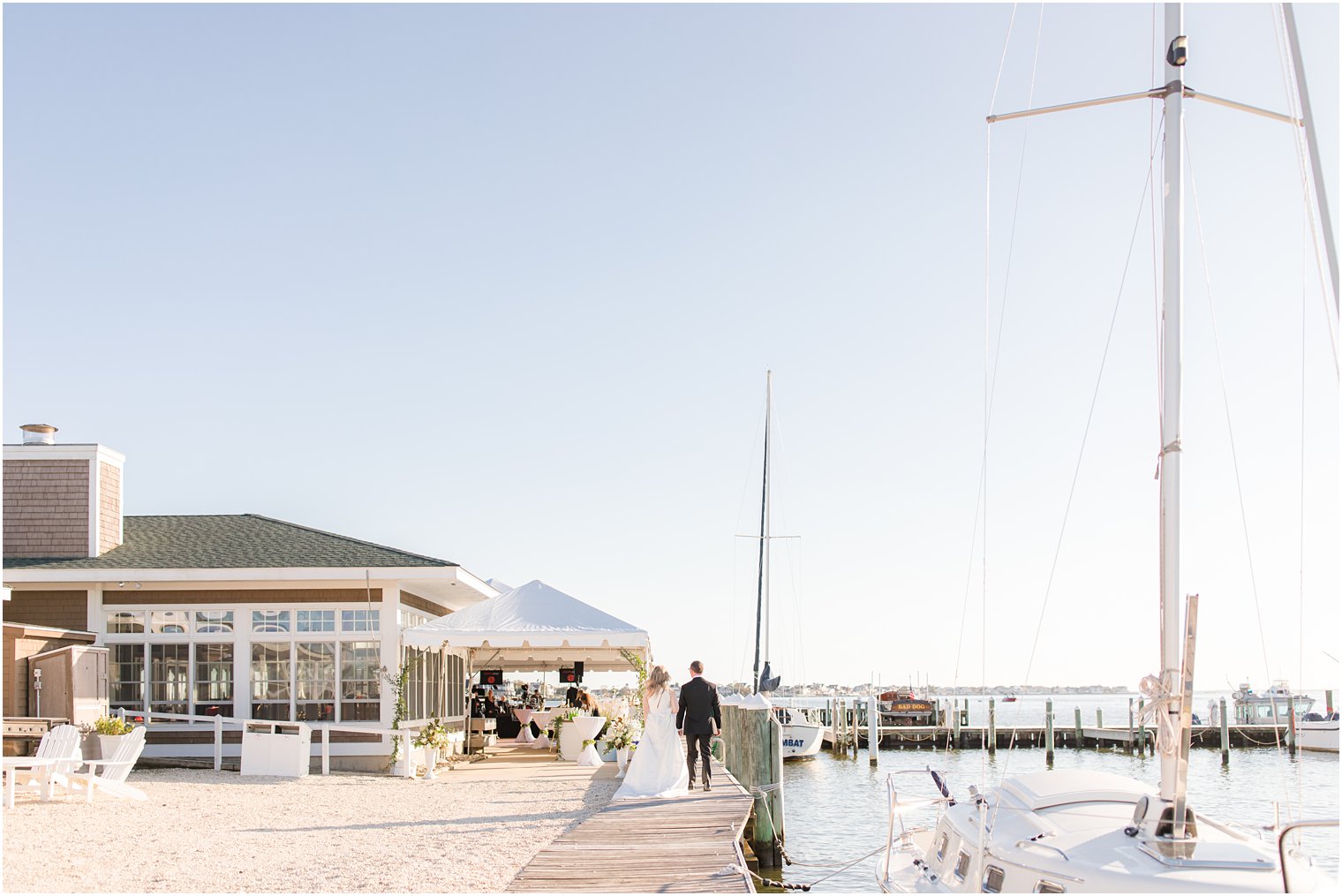 bride and groom walk along pier at Mantoloking Yacht Club