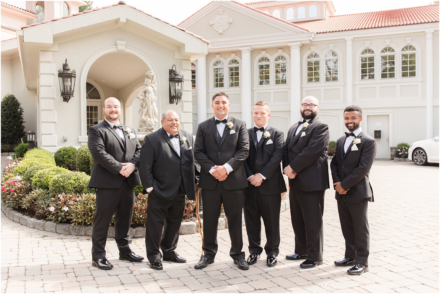 groom poses with five groomsmen outside Nanina's in the Park