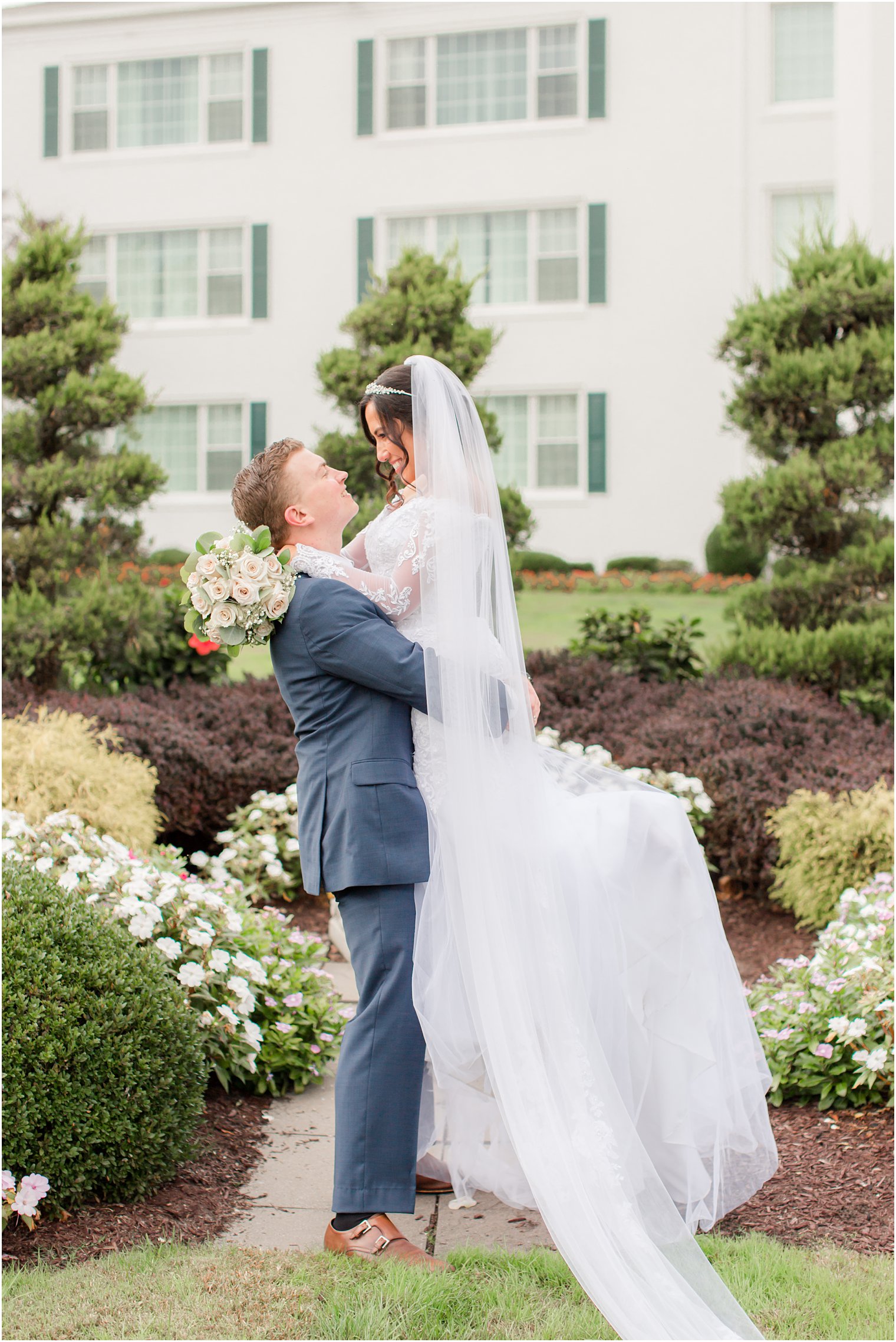 groom lifts bride up in gardens at Seaview Hotel