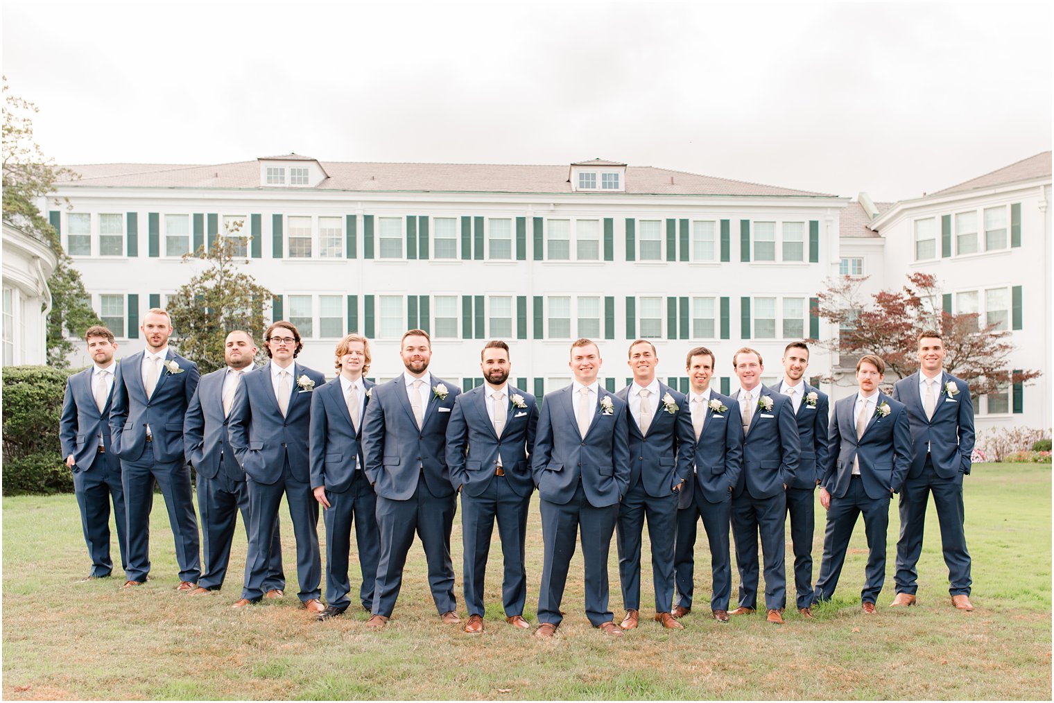 groom and groomsmen in navy suits pose outside Seaview Hotel