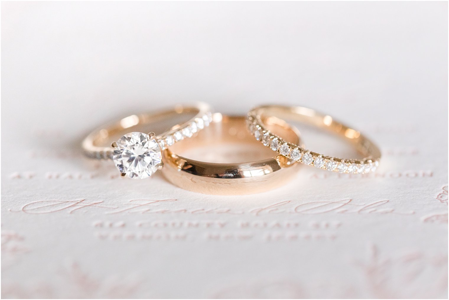 gold wedding rings rest on wedding invitation