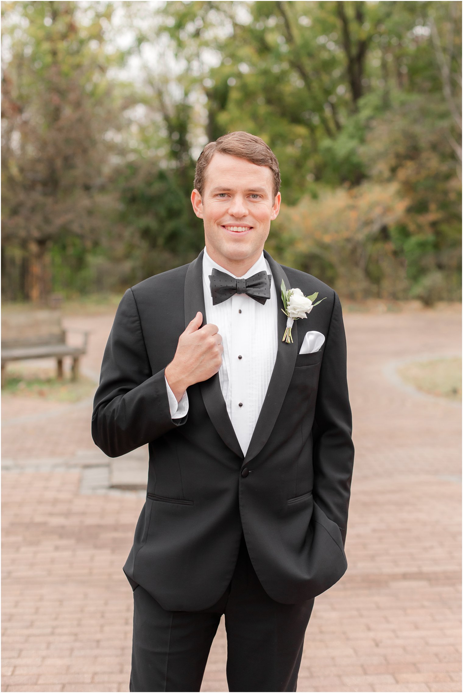 groom in classic black tux holds lapel