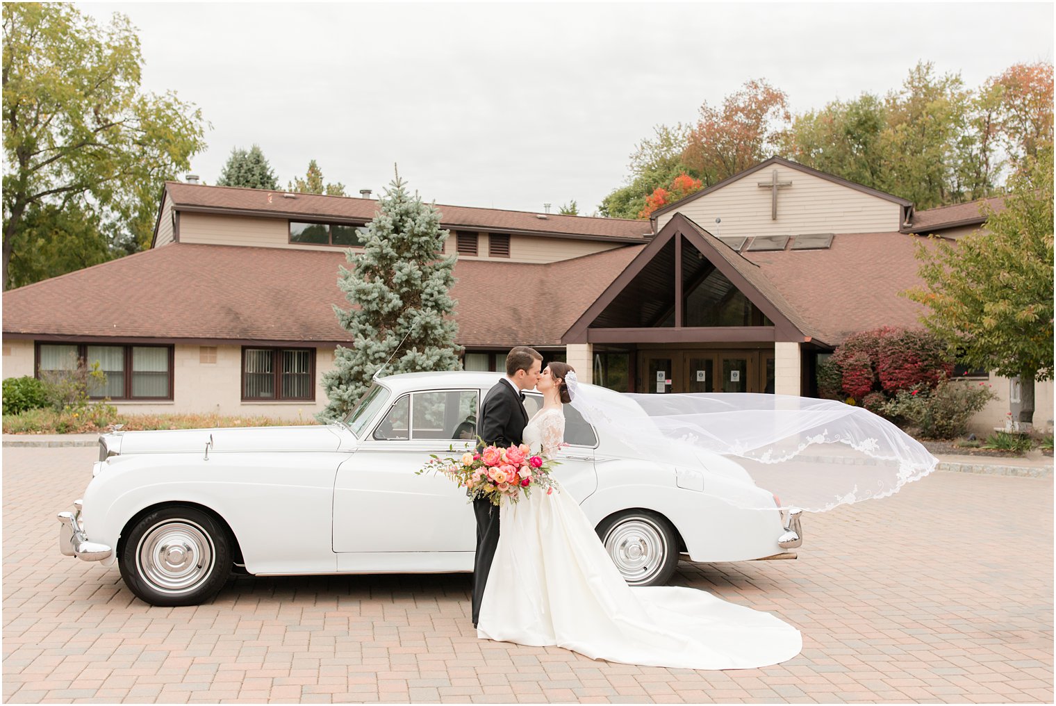 bride and groom kiss by classic Bentley 