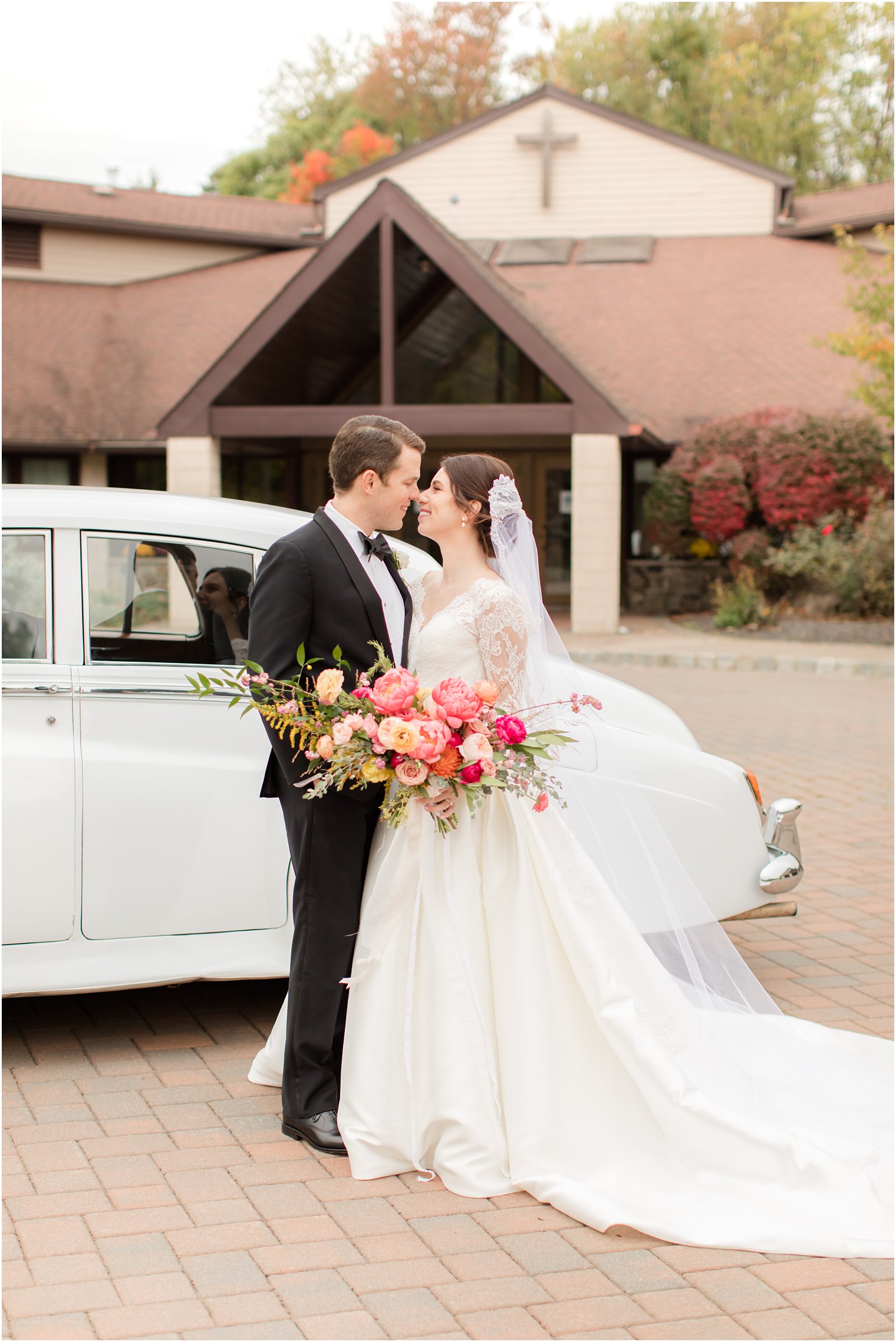 newlyweds kiss by classic Bentley 
