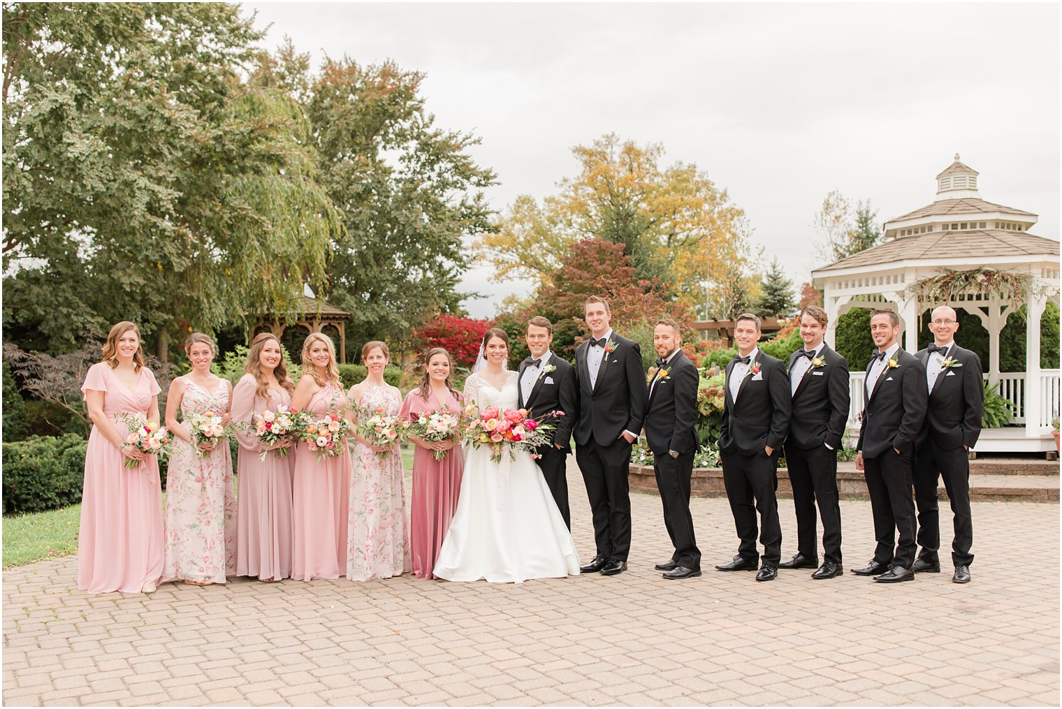 bridal party with mismatched pink floral gowns poses in New Jersey