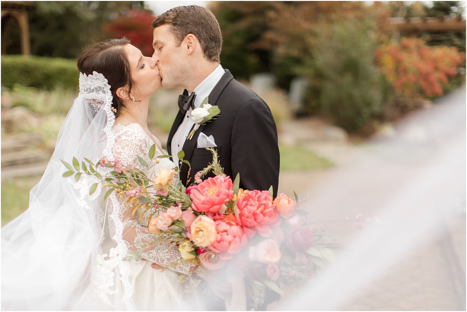 bride and groom kiss with veil wrapped around them