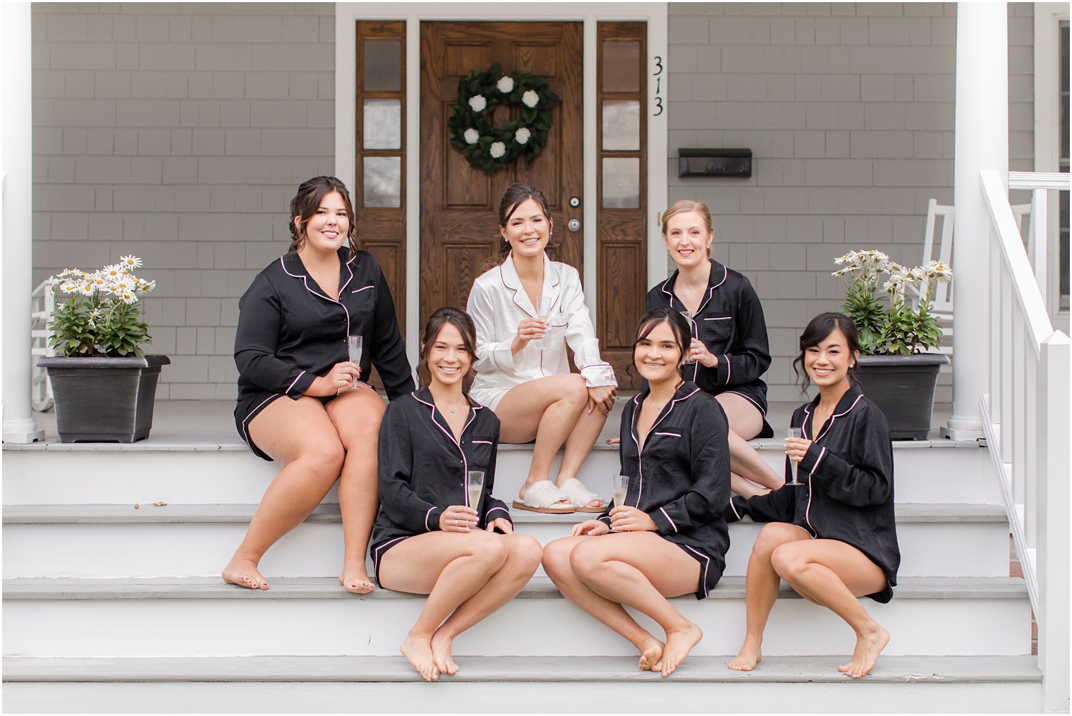 bride sits on front steps with bridesmaids in New Jersey