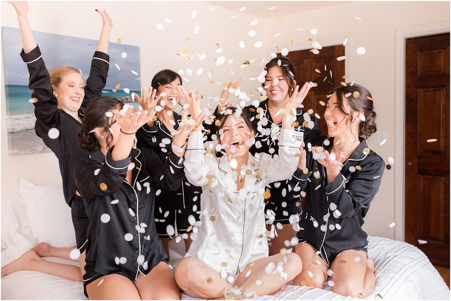bride and bridesmaids toss confetti on bed