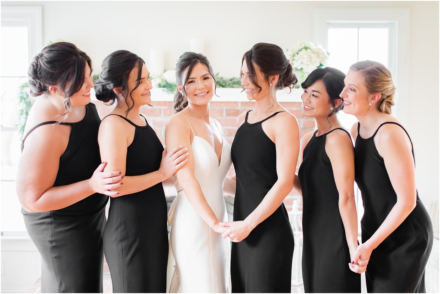 bride poses with five bridesmaids in black gowns