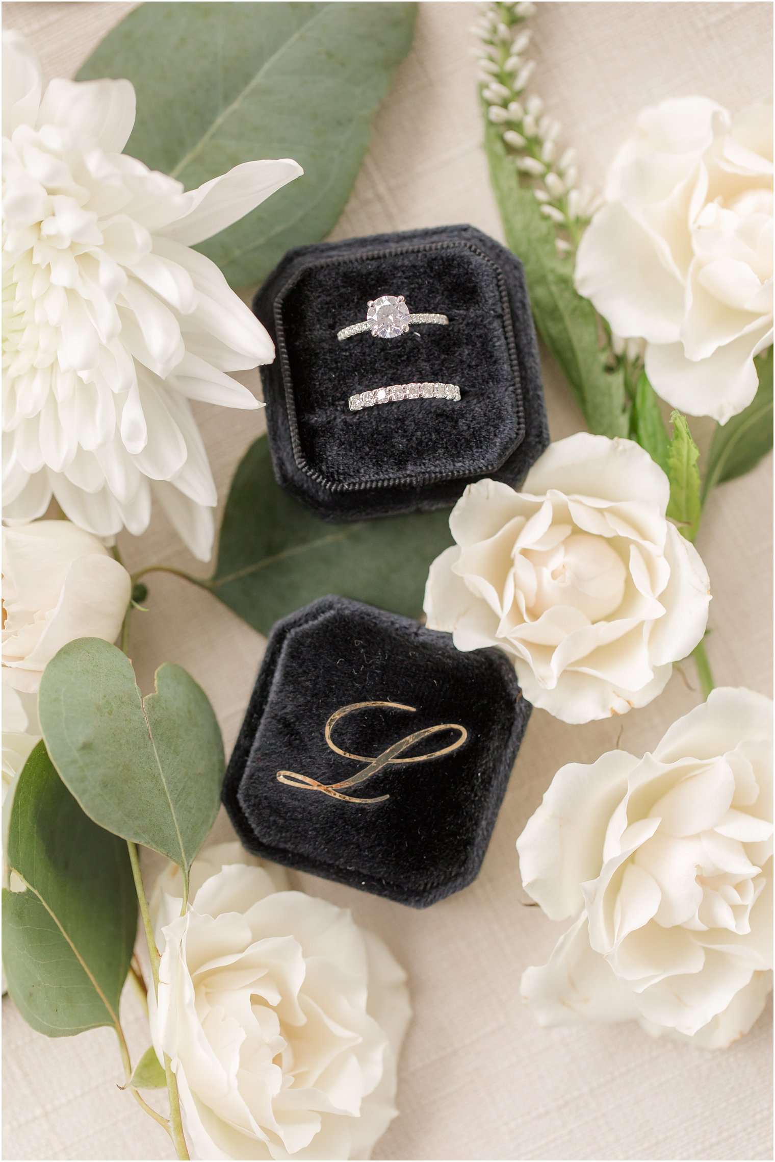 bride's rings rest in black jewelry box monogrammed with L
