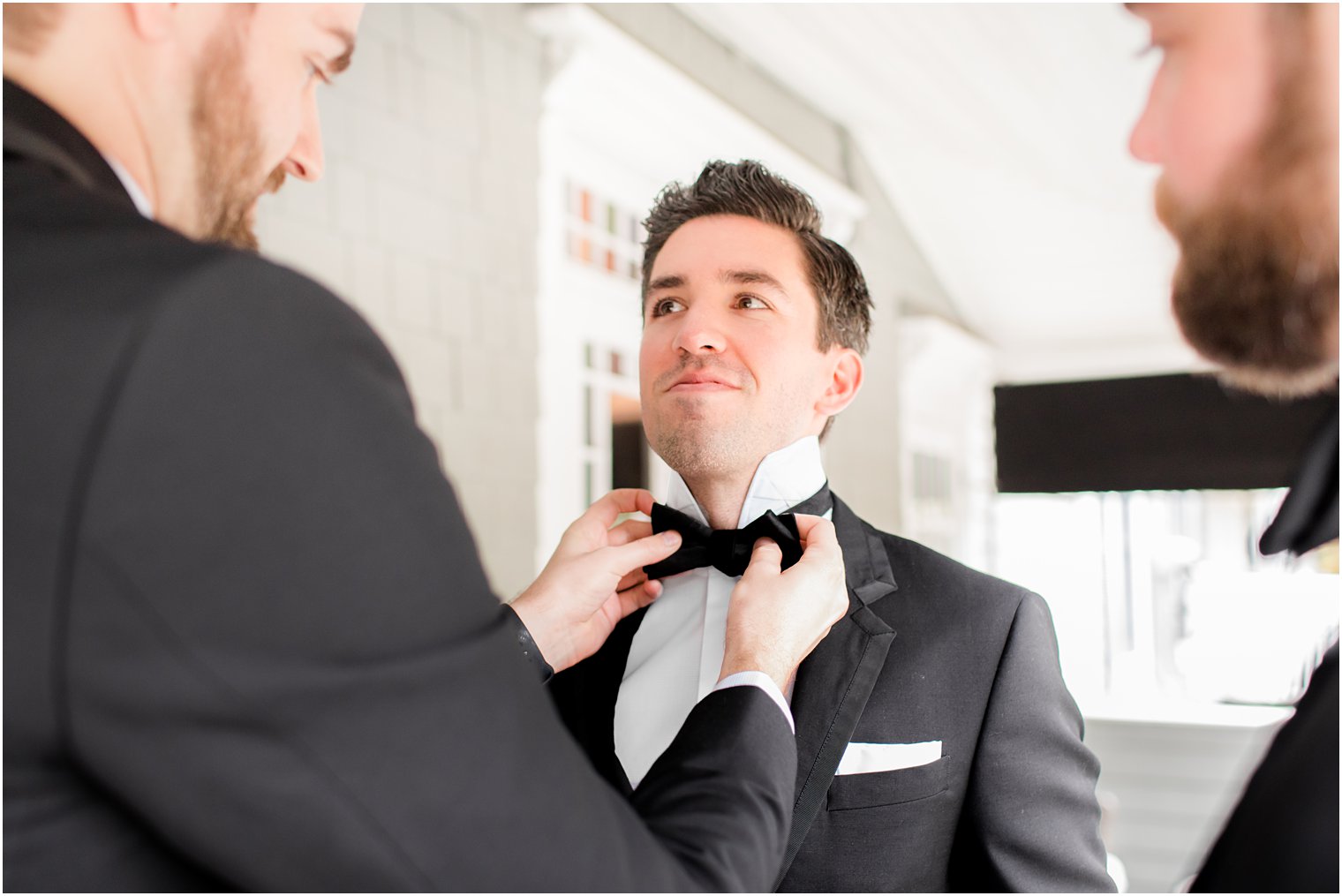 groomsman adjusts tie for groom in New Jersey