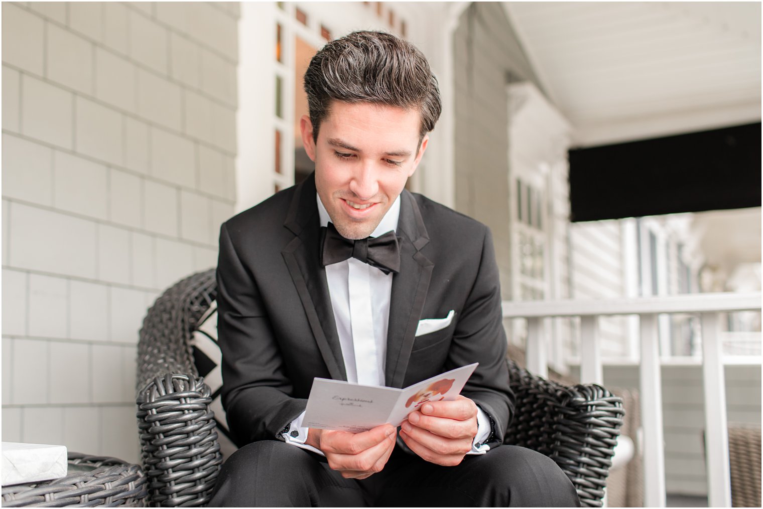 groom sits on porch reading letter from bride