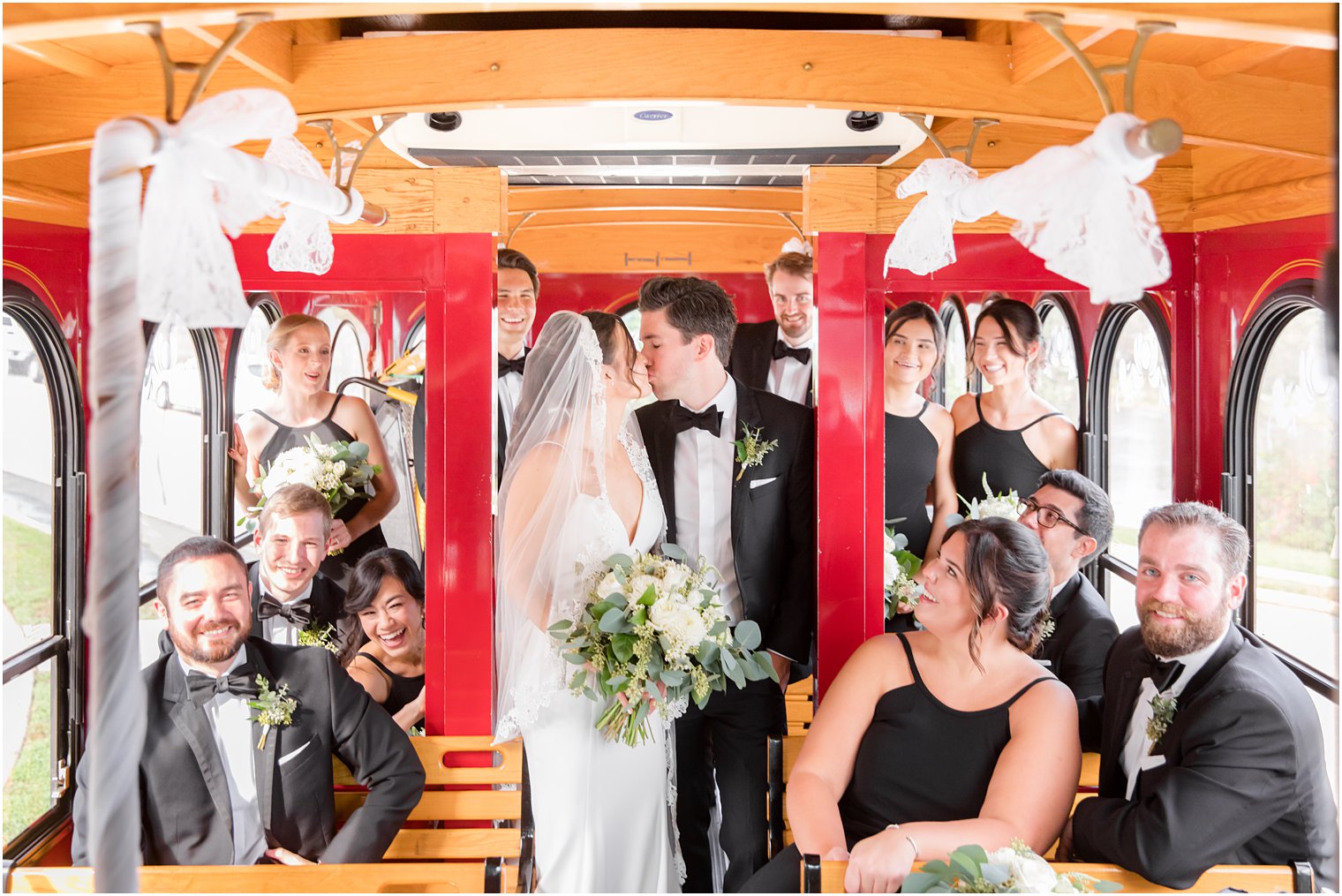 newlyweds kiss on trolley with bridal party watching