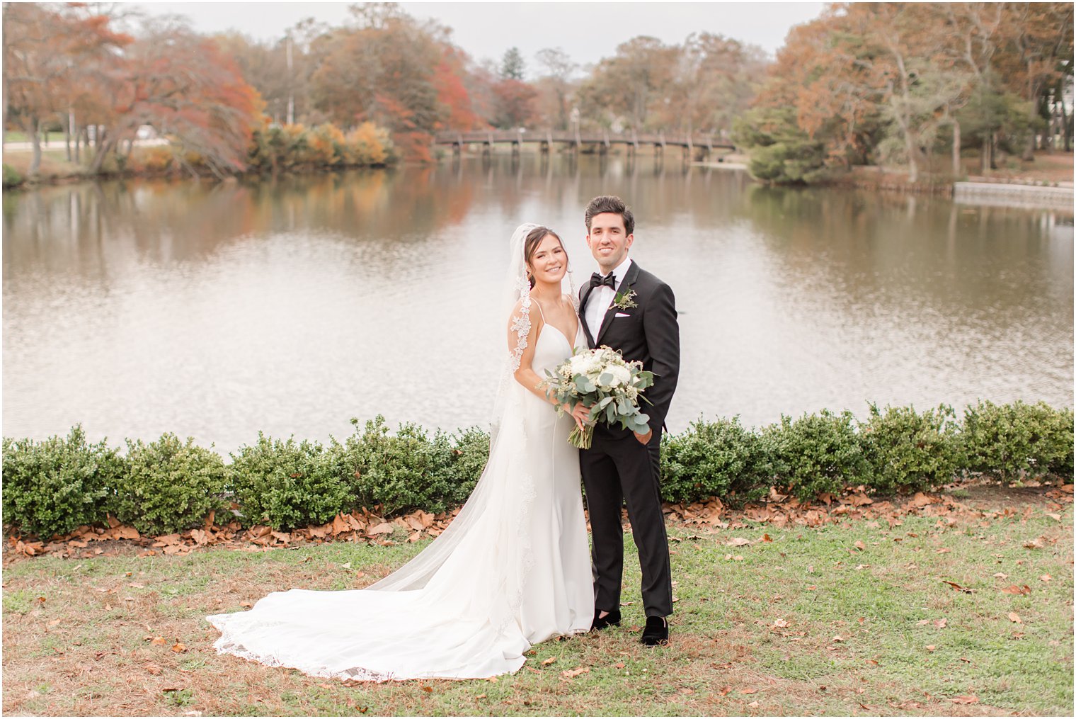 bride and groom pose by lake in Divine Park in Spring Lake NJ
