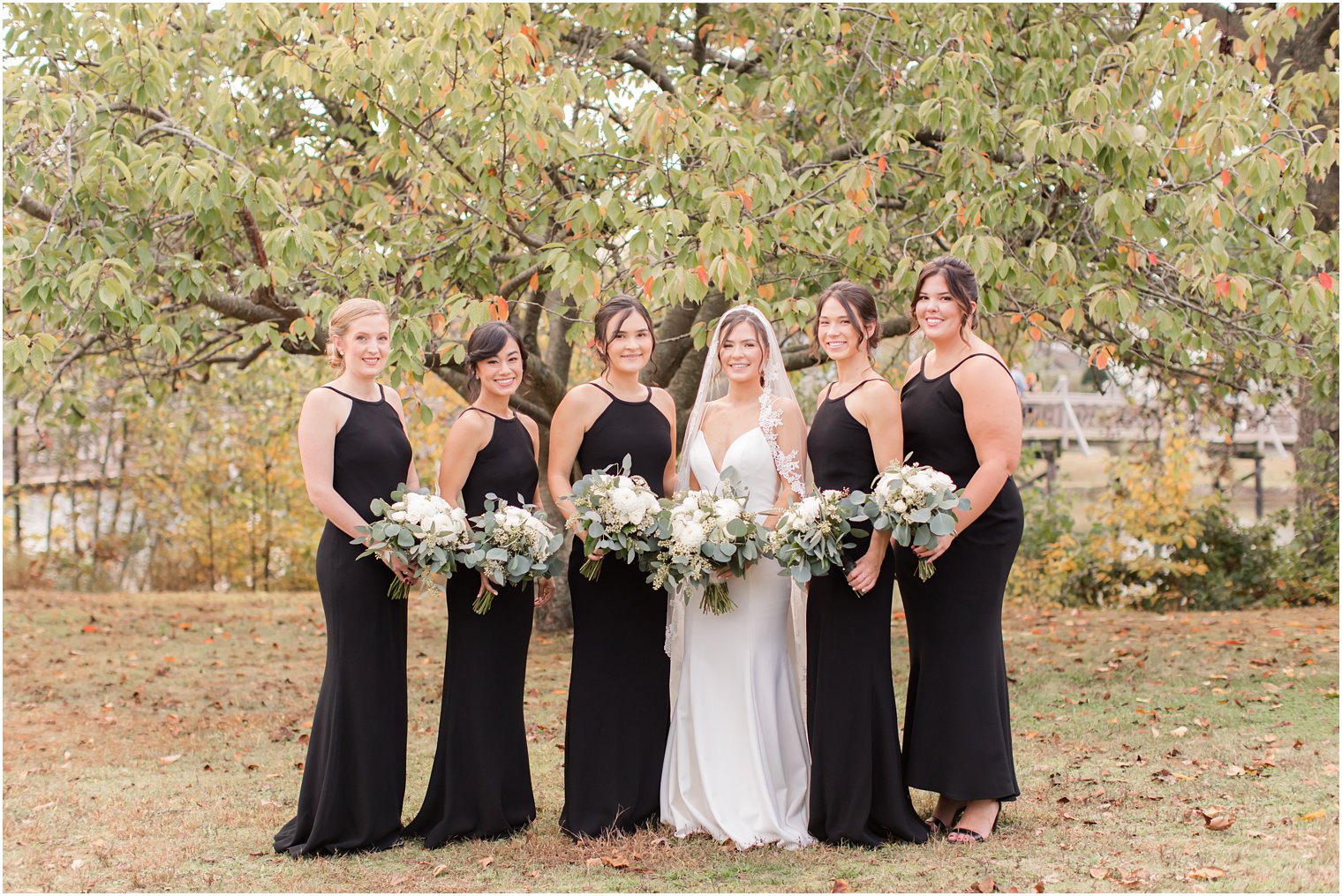 bride poses with bridesmaids in black gowns before The Mill Lakeside Manor wedding