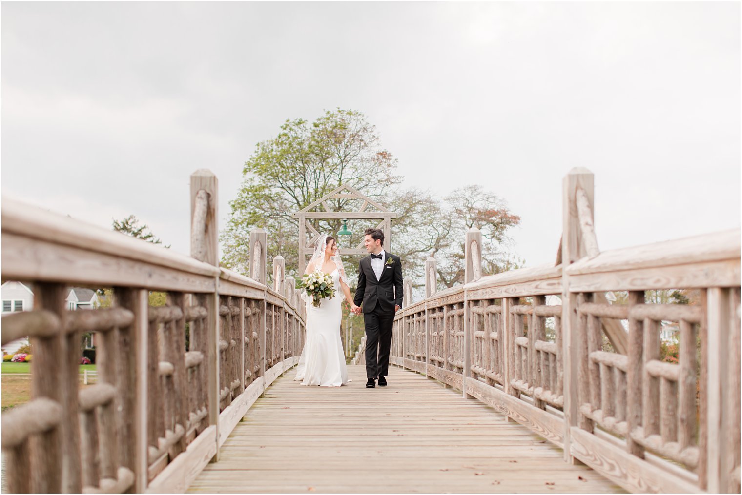 newlyweds walk on bridge in Divine Park