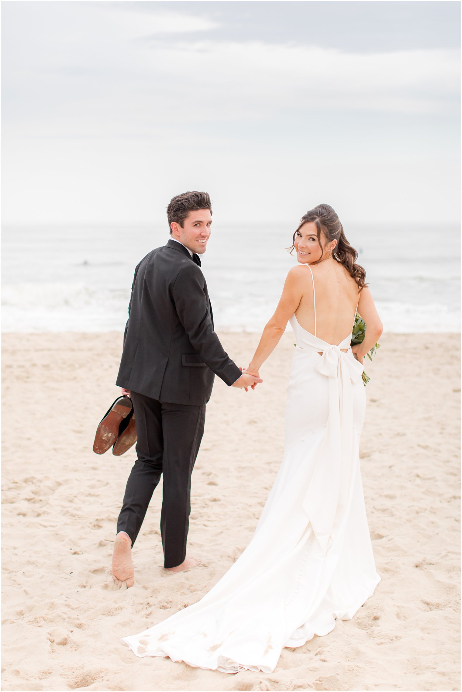 bride and groom walk through sand at Spring Lake Beach 