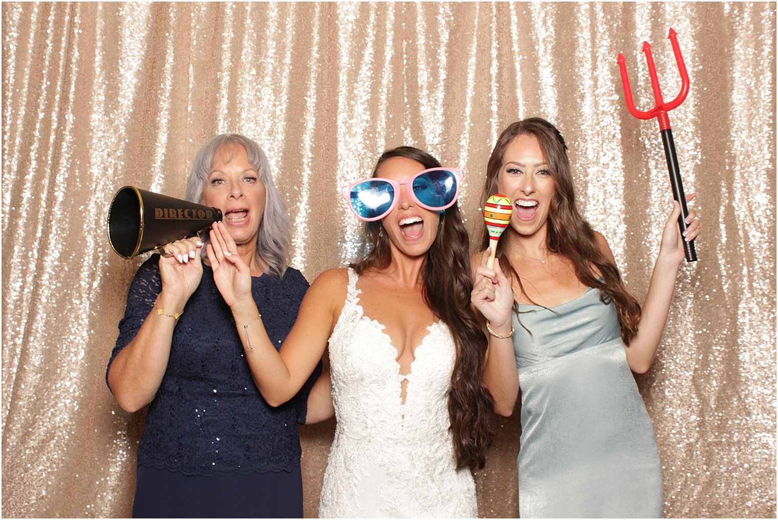bride plays in photo booth with bridesmaid and mom