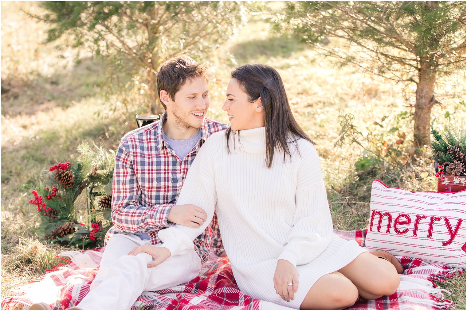 bride and groom sit on holiday blanket during Christmas Tree Farm engagement session