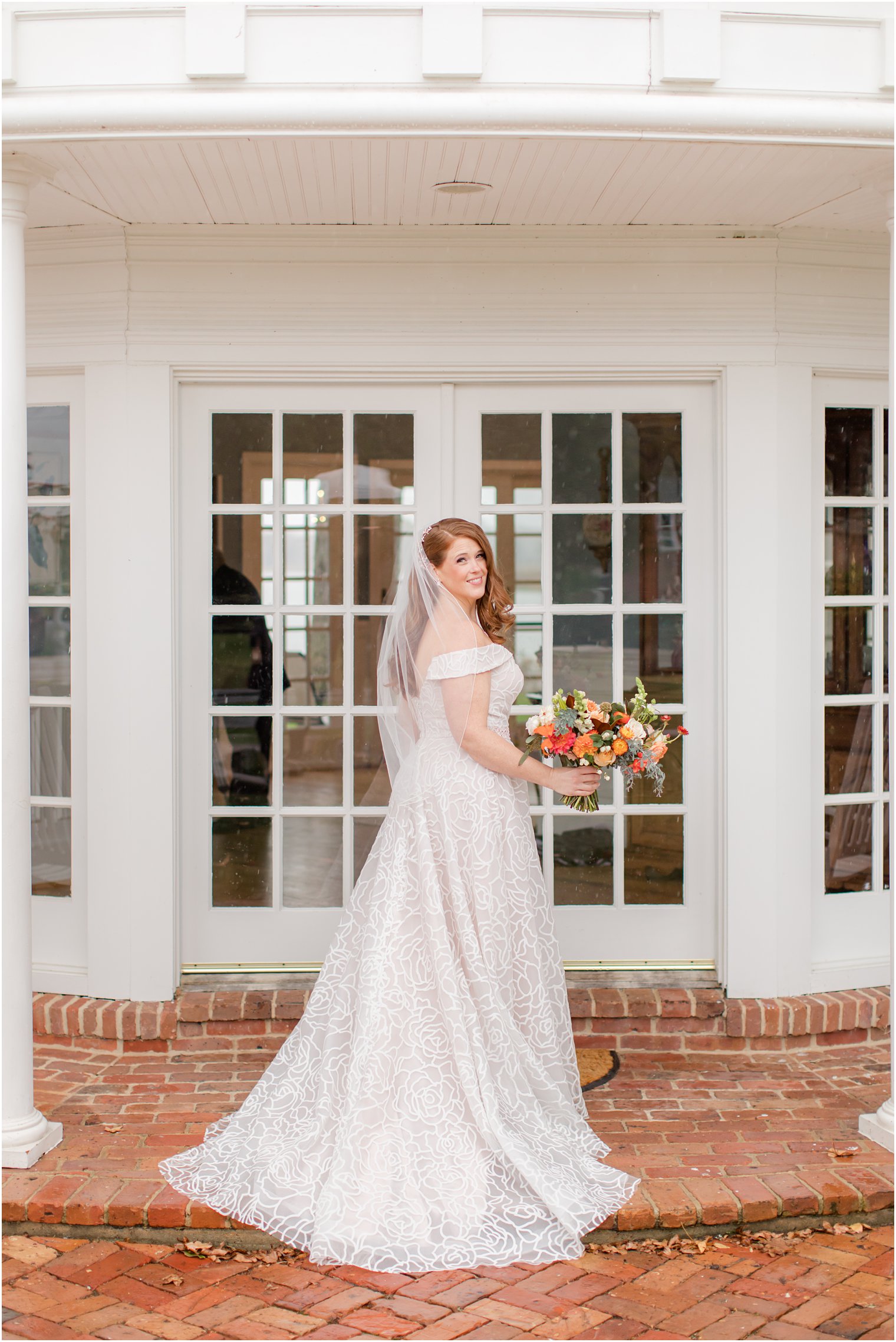 bride poses outside Eagle Manor with veil on shoulders
